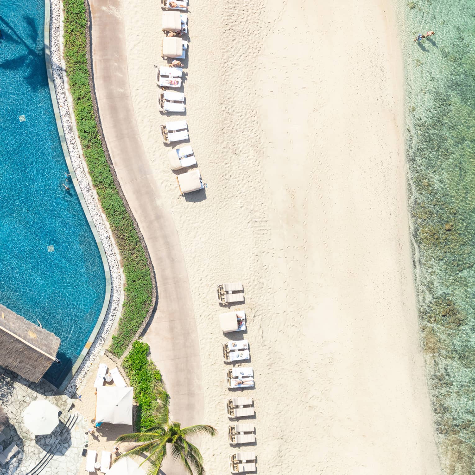 Aerial view of pool, strip of beach and light green ocean water