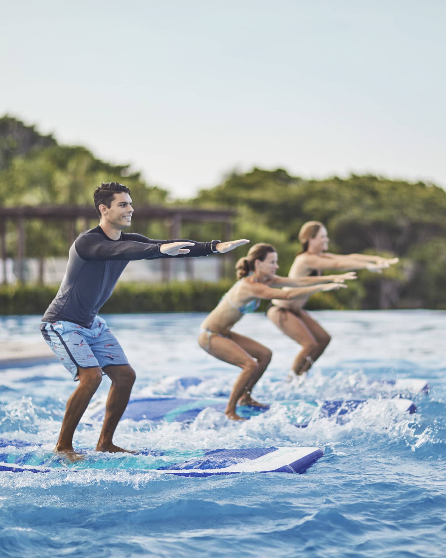 Two guests being instructed how to stand up on surf boards