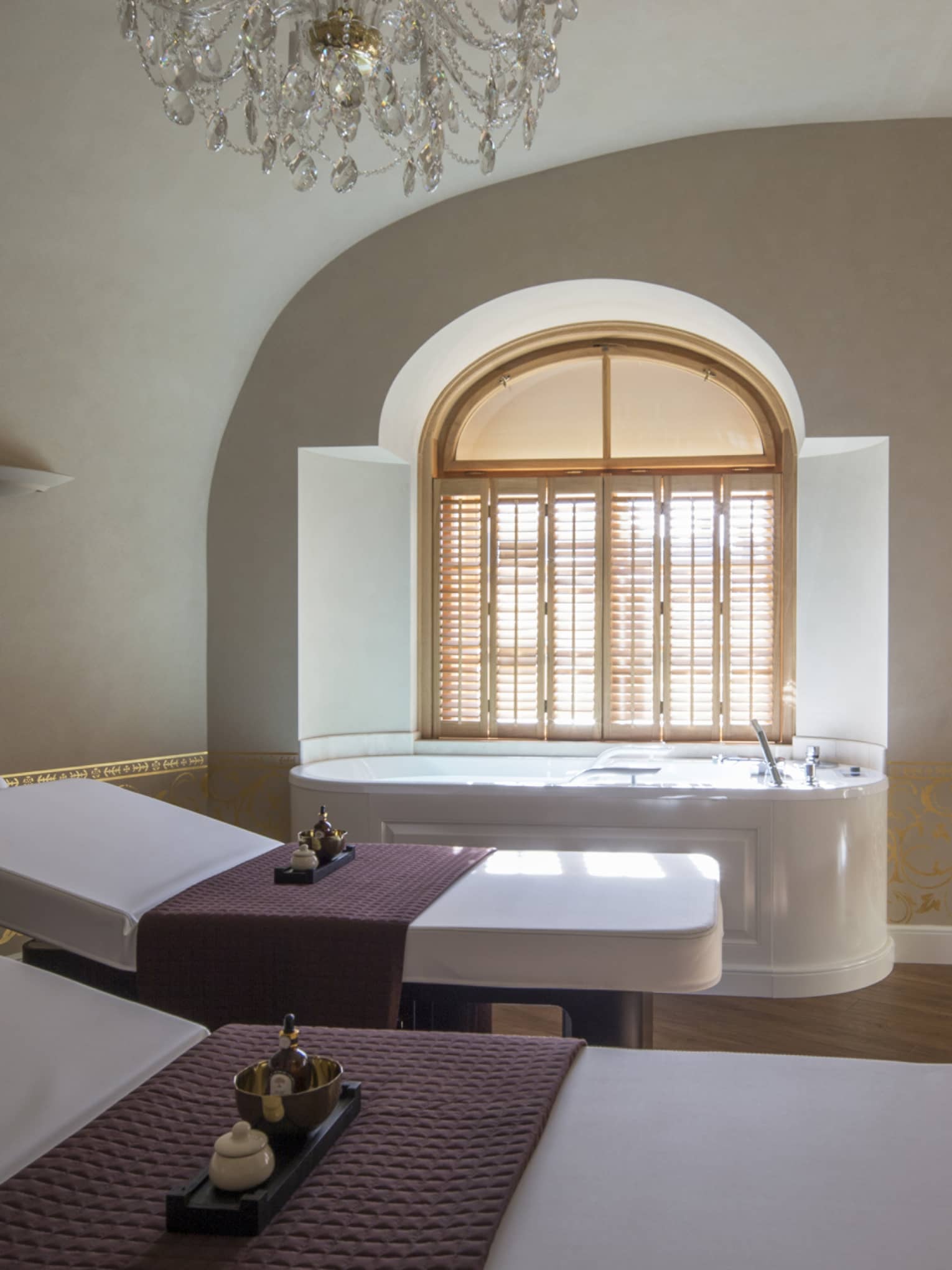 Two white beds beside spa tub in dimly-lit room at the Vltava Suite at AVA Spa