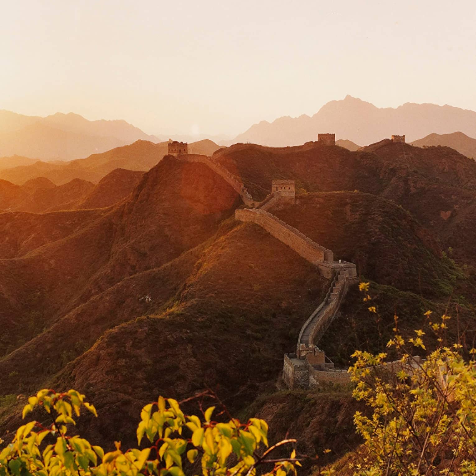 Sunset over mountain, trees with Great Wall of China along side