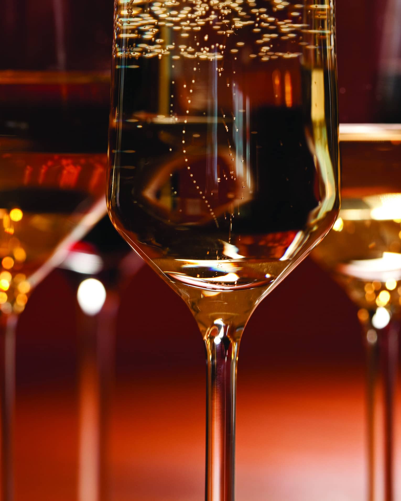 Up close shot of three crystal wine glasses with a red background