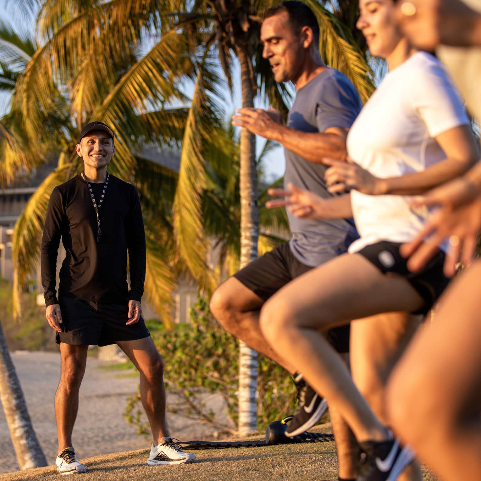 Fitness instructor leading an outdoor workout class with three guests.