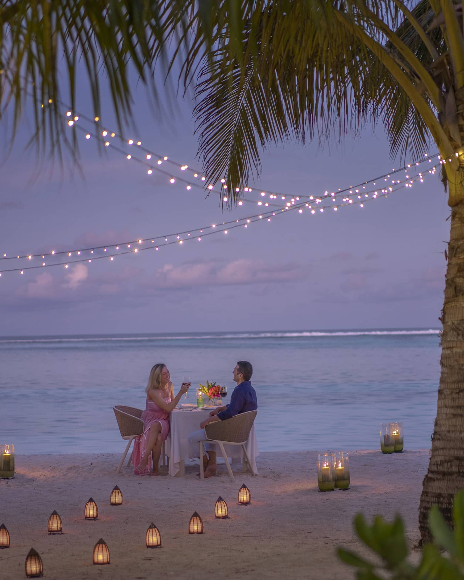 Man and woman dine at table for two alone on decorated beach