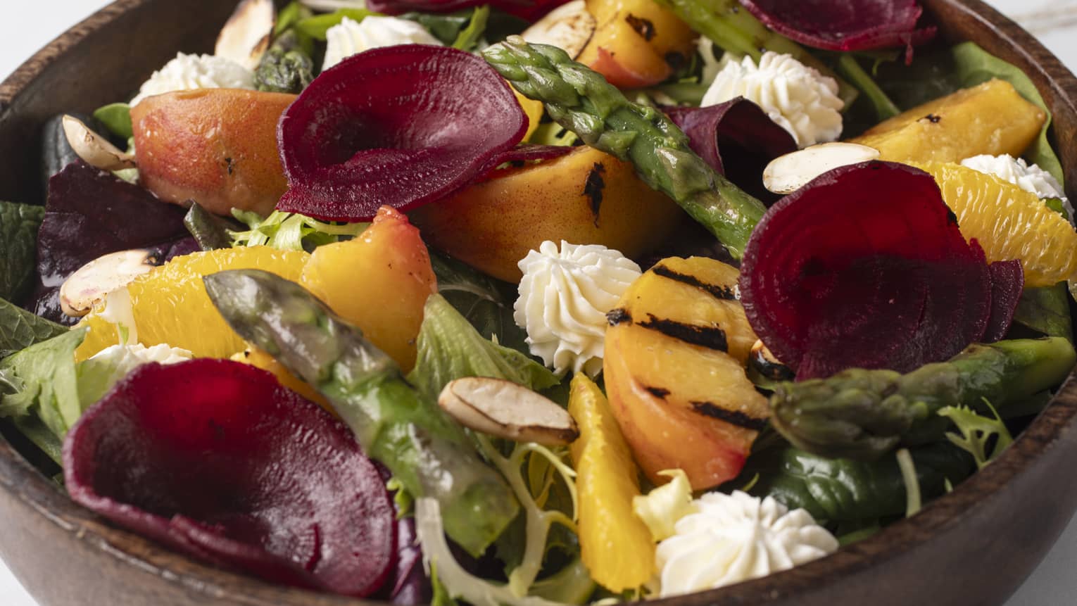 An insalata primavera served in a brown wooden bowl.