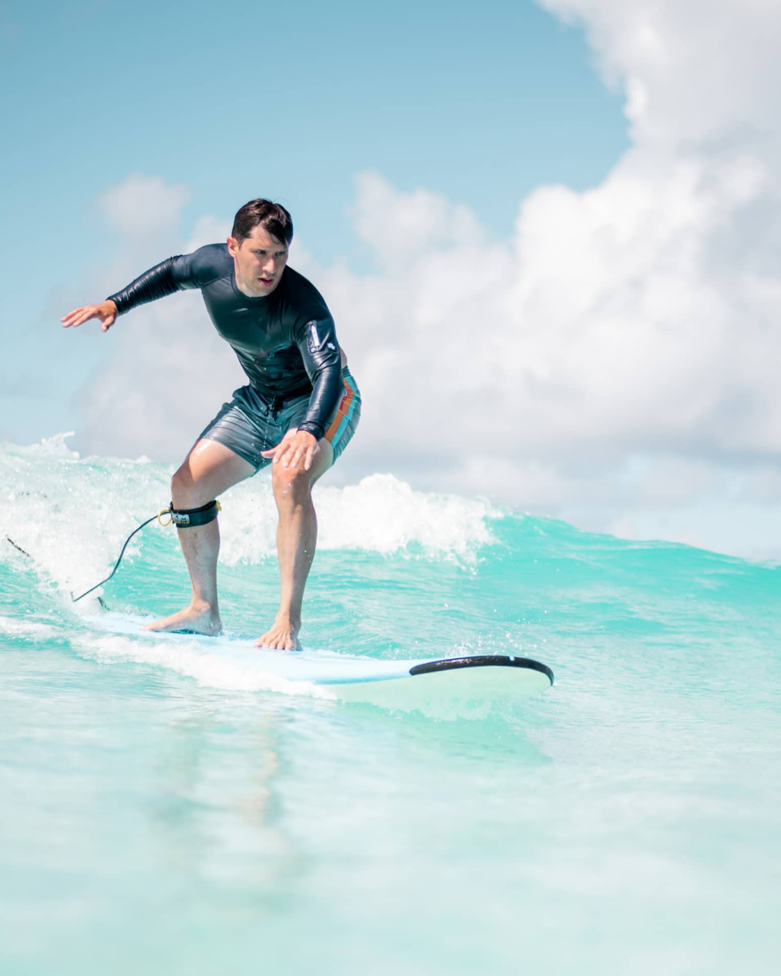 Man balances on surf board over wave