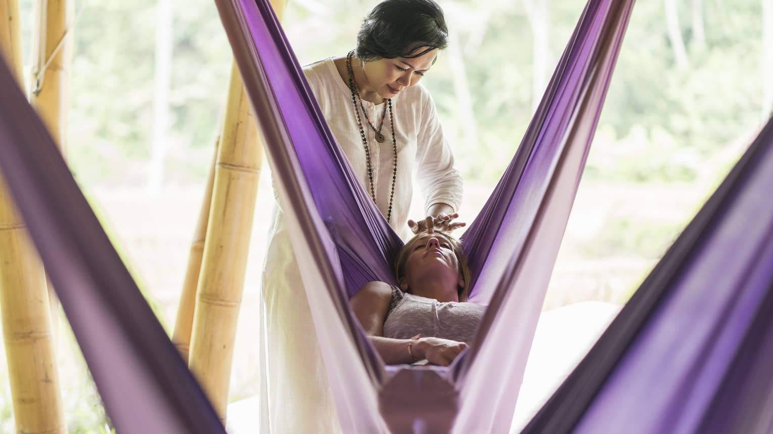 A Four Seasons yoga instructor massages the forehead of a guest during a sacred nap