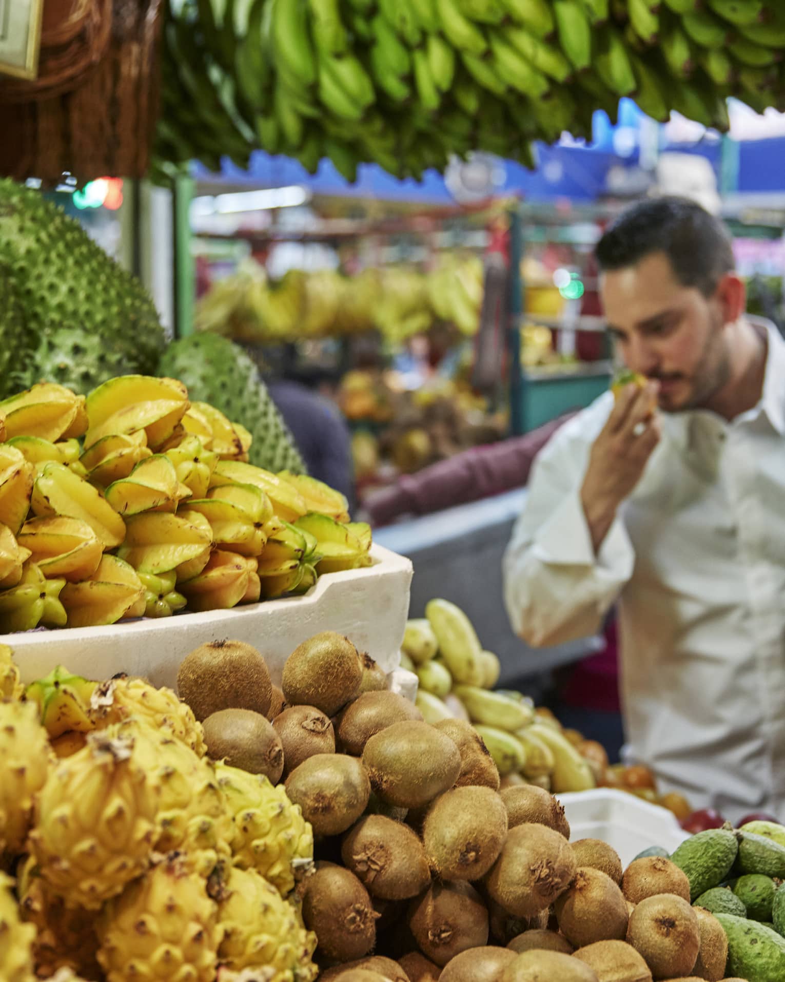 Chef smells tropical fruit at stand in market 