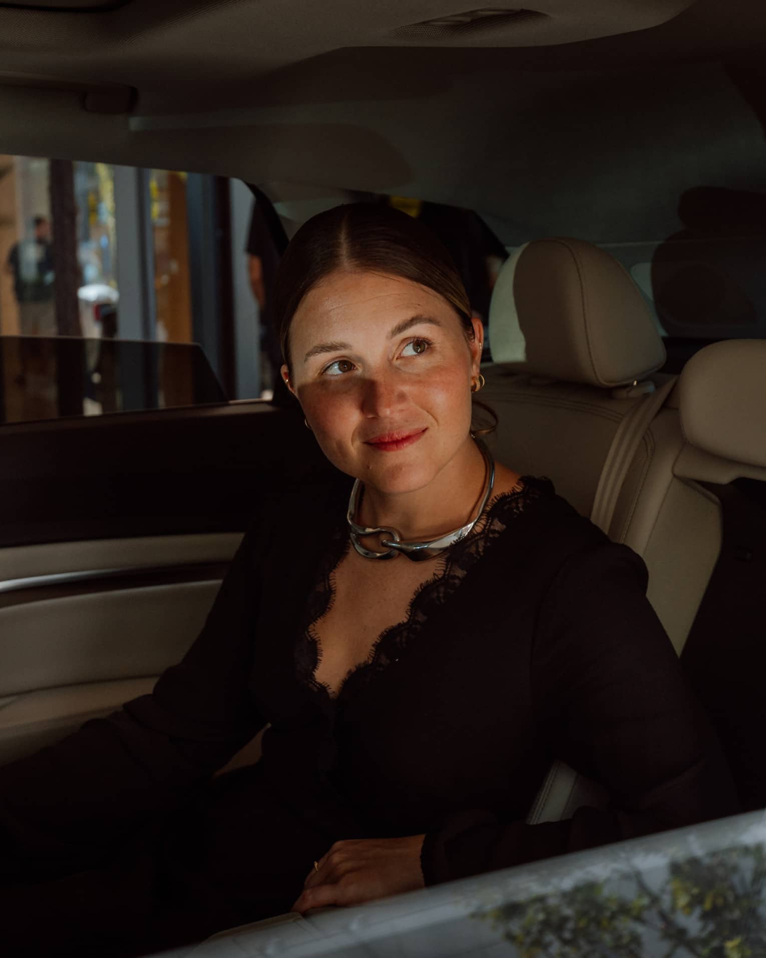 Person sitting in luxury vehicle backseat with windows slightly down