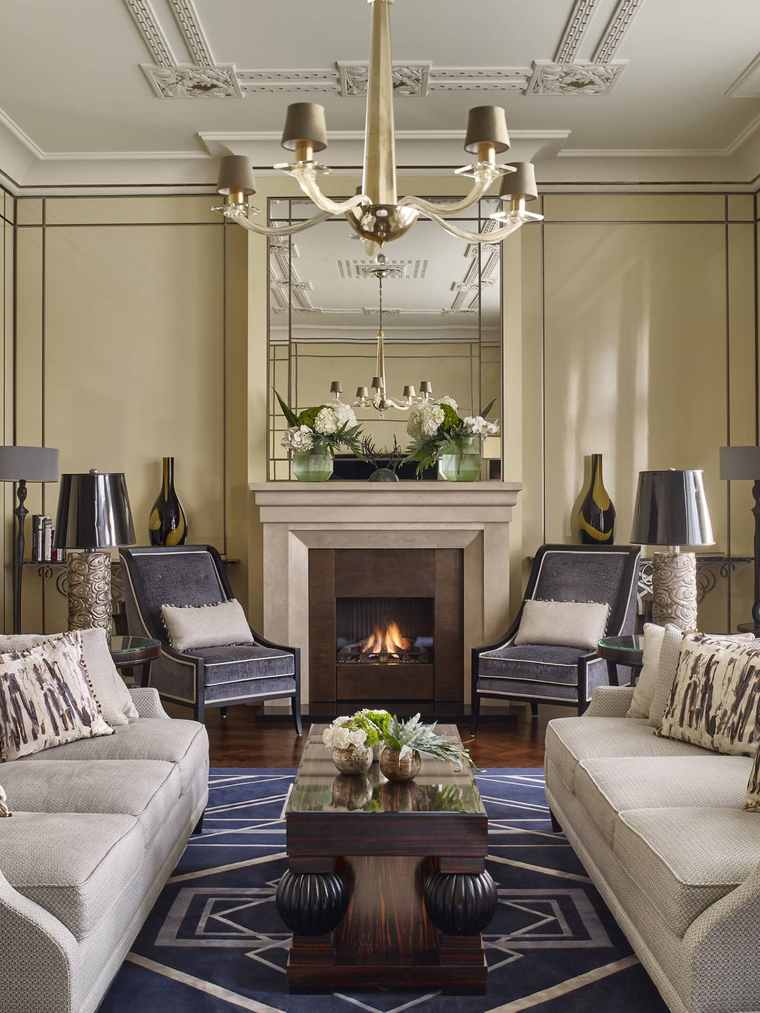 Elegant living room with two sofas, a fireplace and armchairs around a central coffee table