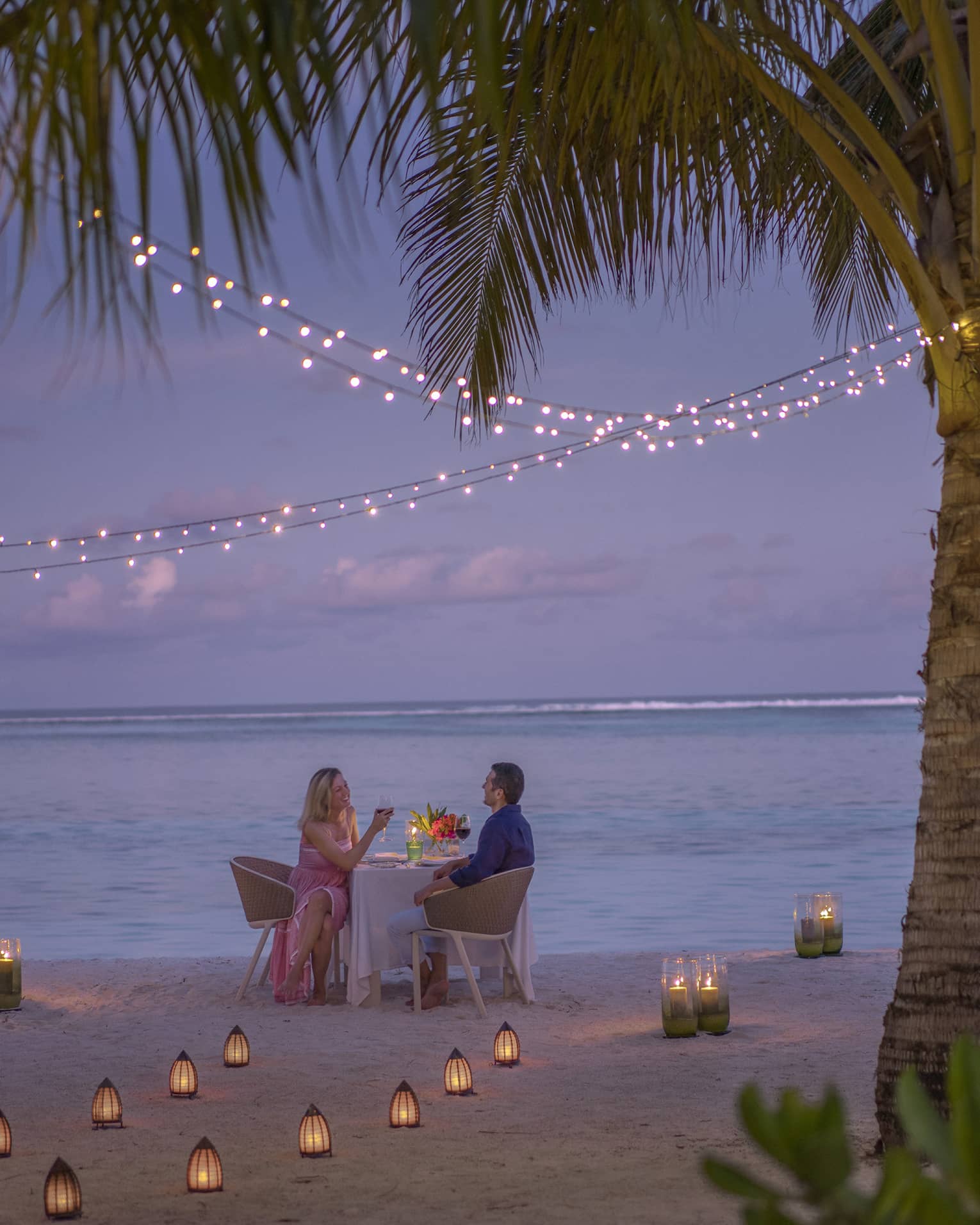 Man and woman dine at table for two alone on decorated beach