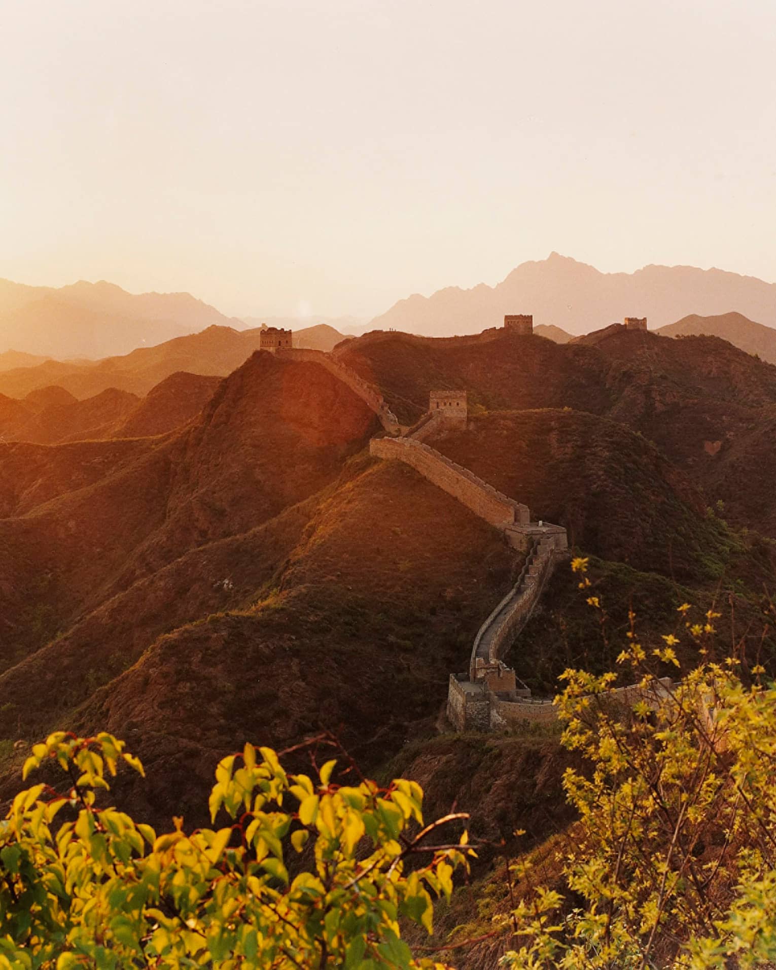Sunset over mountain, trees with Great Wall of China along side
