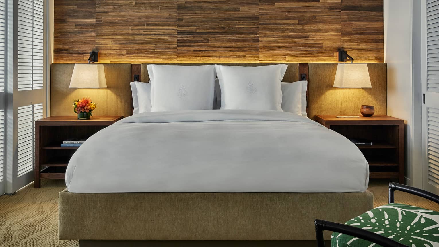 Bed with retro-style wood and upholstered headboard, nightstands, lamps, rustic wood wall