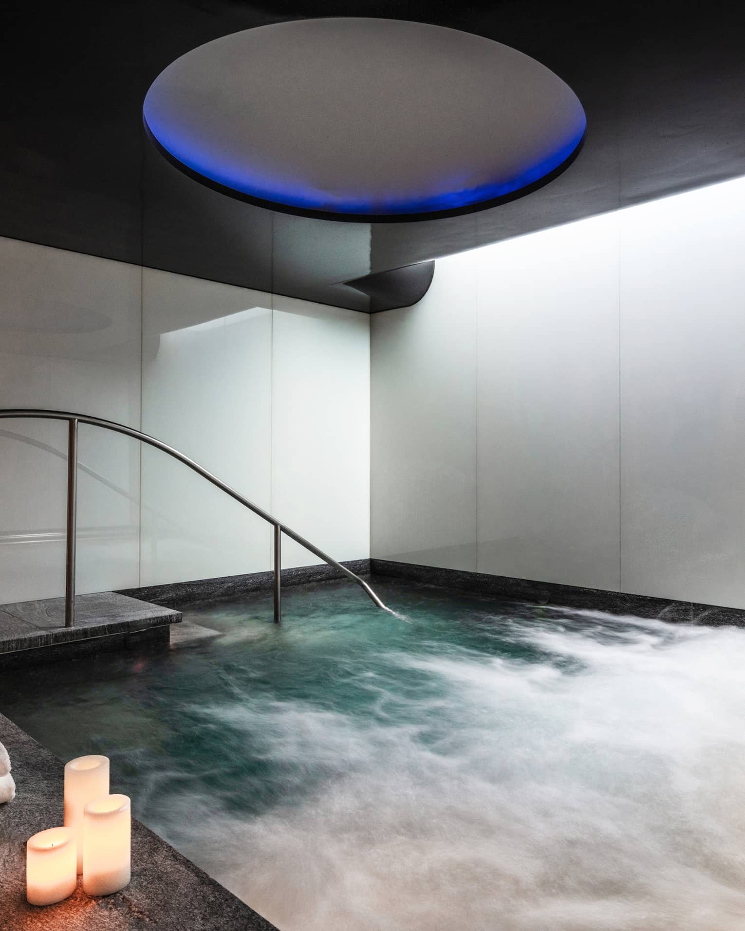 An indoor whirlpool with candle on the ledge.