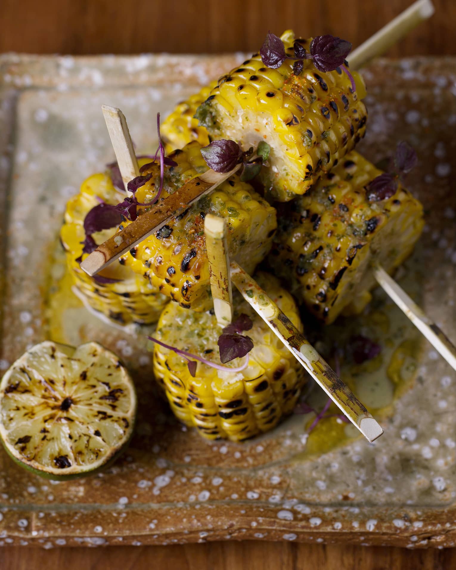 Grilled corn with a lime on a pottery plate
