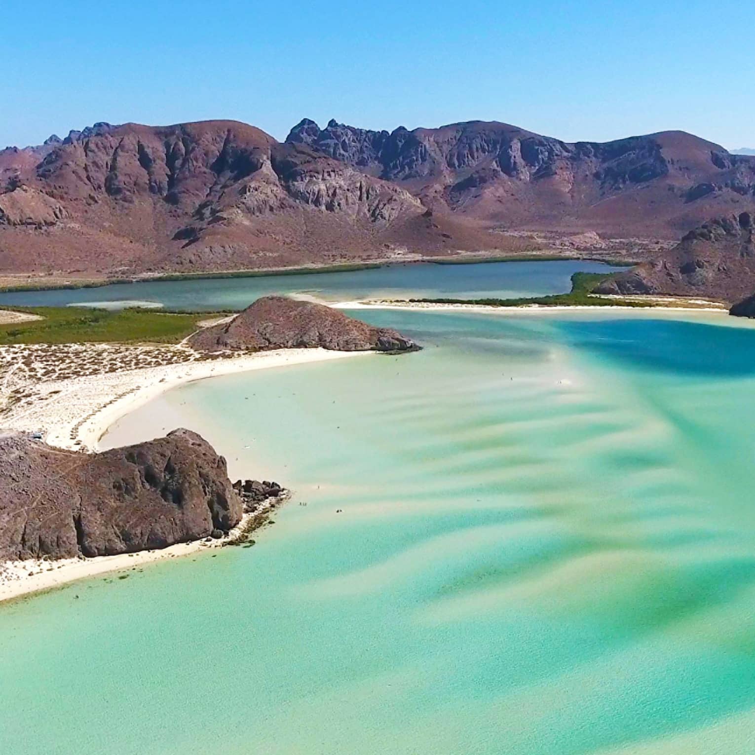 A beach shore with bright blue green water.