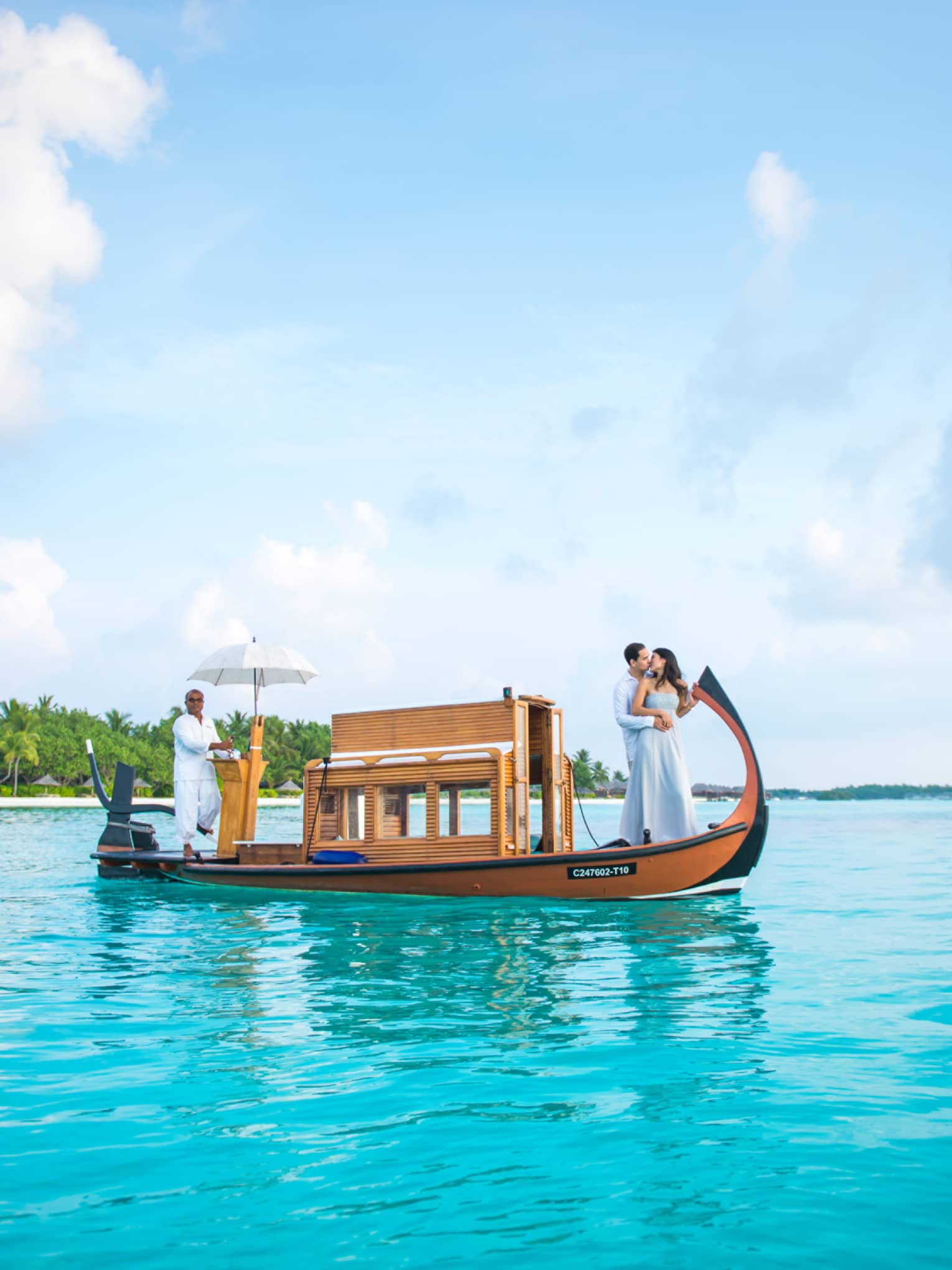Couple embracing on wooden boat with man at back boat under umbrella