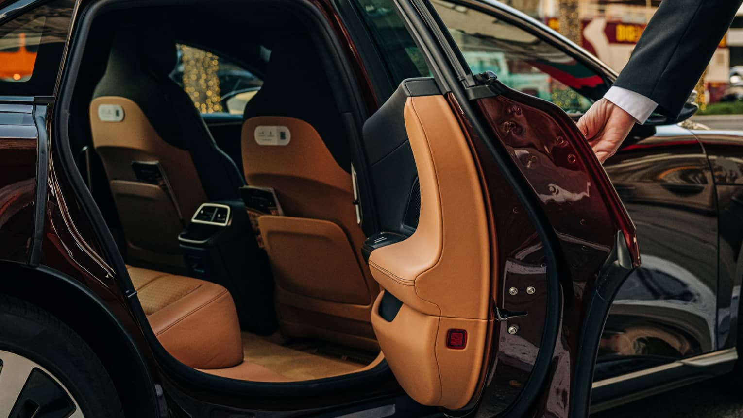 Person wearing a suit and opening a car door