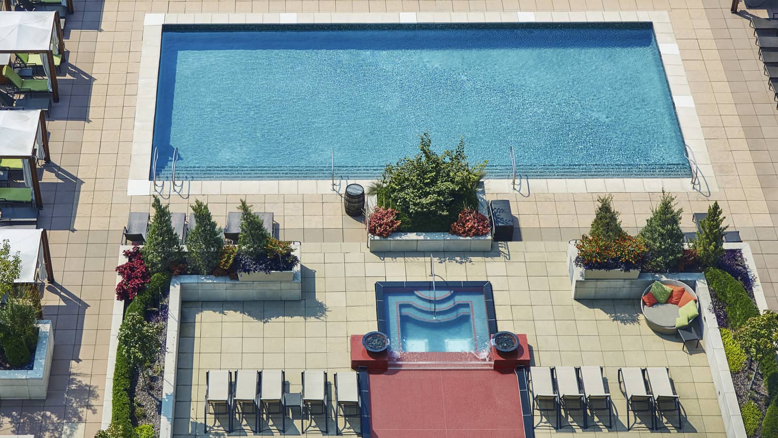 Aerial view of rooftop outdoor swimming pool and rows of patio chairs, cabanas 