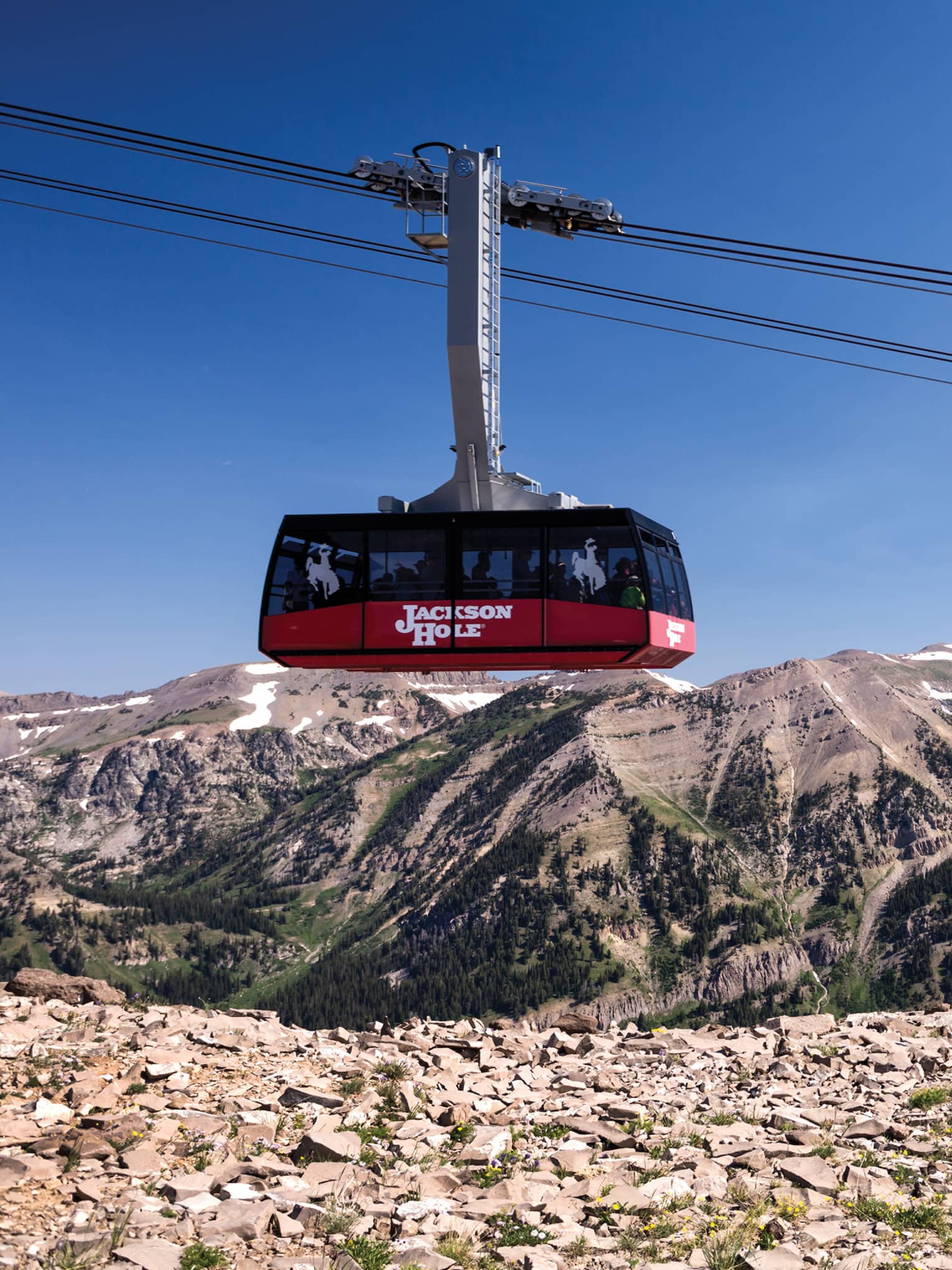A family of four watches from a cliff as a ski lift passes by