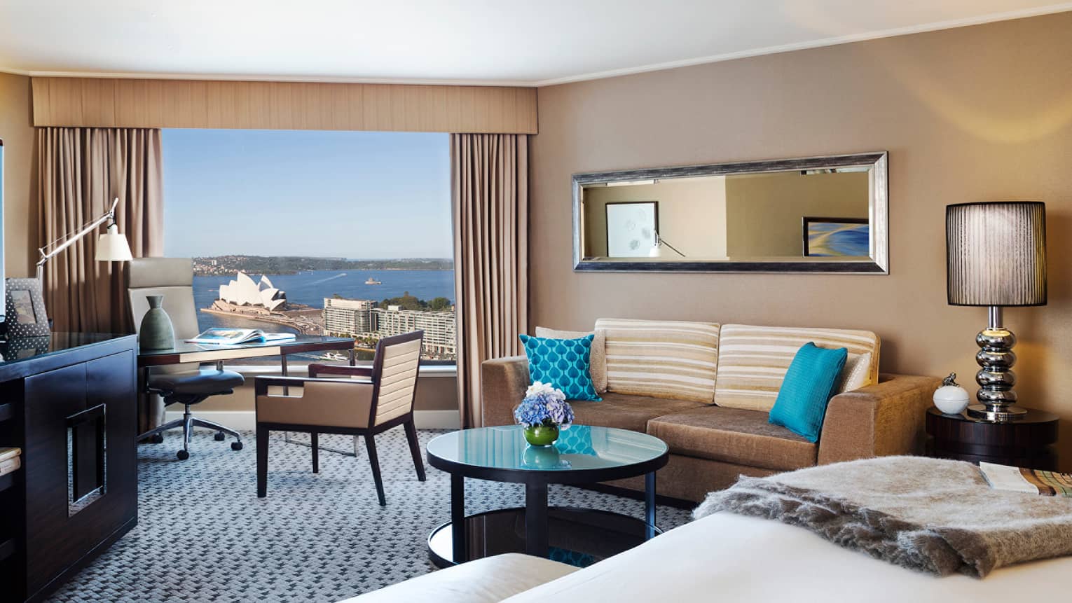 Premier Full Harbour Room, edge of bed, table with flowers, velvet sofa and blue pillows