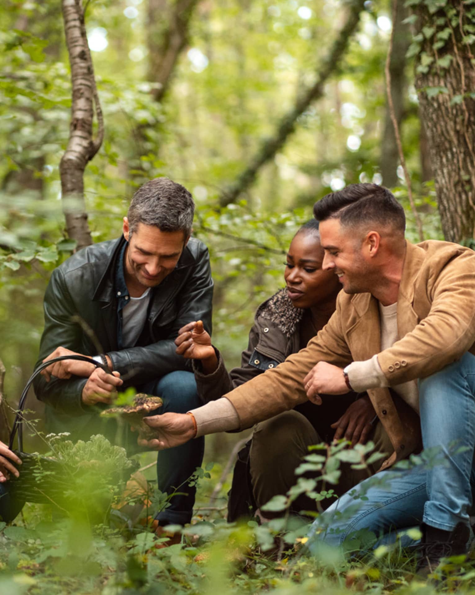 A group of people foraging in a forest, closely examining wild mushrooms they have gathered in a basket