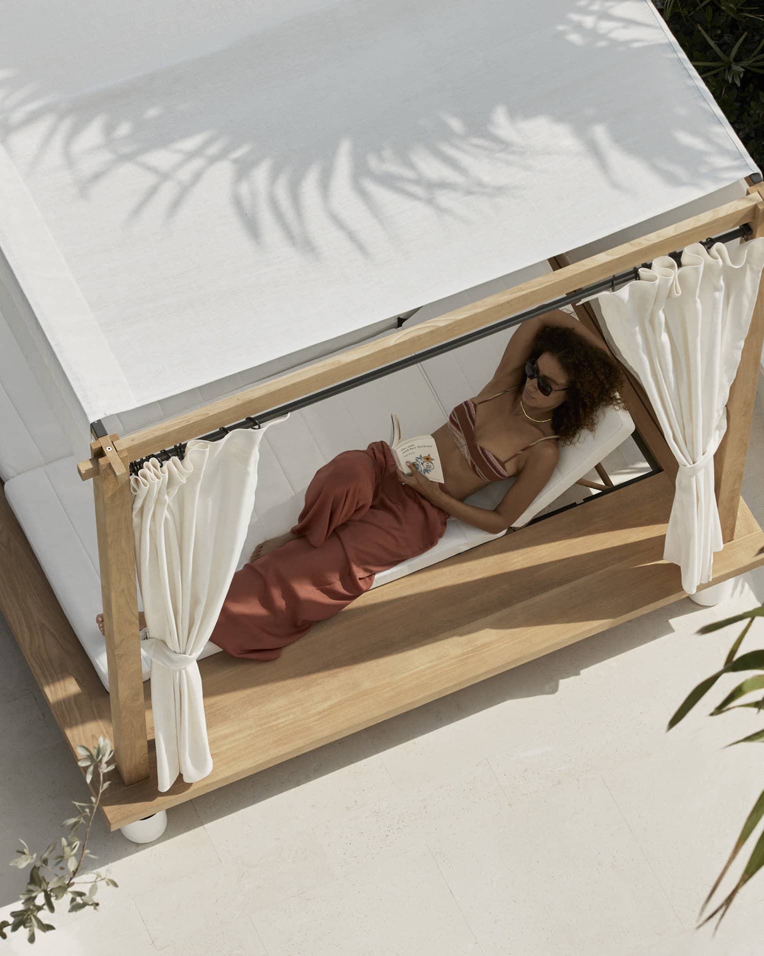 Aerial view of woman lounging in a covered poolside daybed