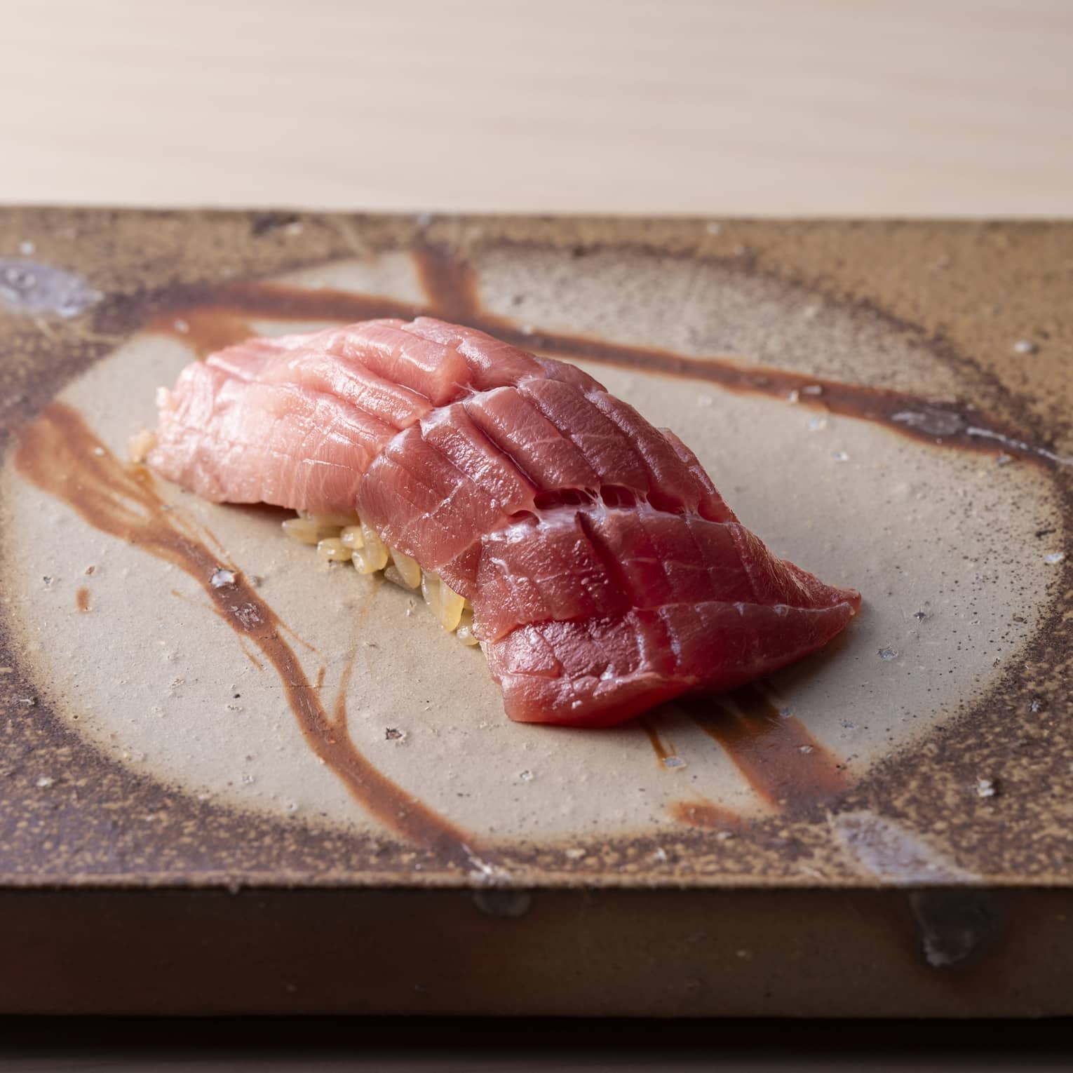Premium fatty tuna nigiri with delicate knife cuts, served on artisanal Japanese ceramic at Sushi Ginza Onodera.