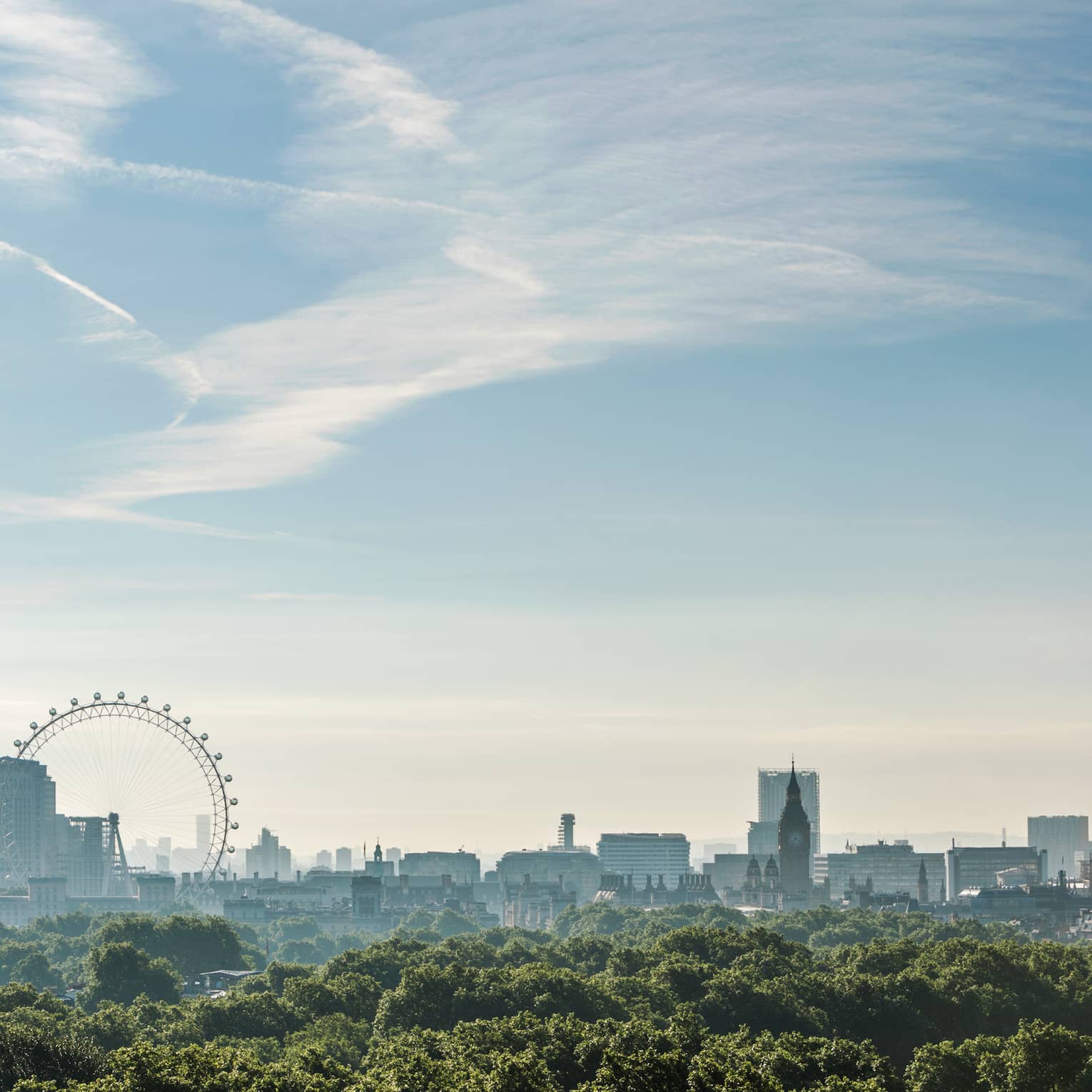 Panoramic view of the London skyline from a high vantage point, showcasing a clear blue sky and lush greenery in the foreground. Prominent landmarks visible include the Shard, the London Eye, and historical architectural silhouettes of the city. The photo captures a serene morning with soft sunlight casting gentle hues over the urban landscape.,Panoramic view of the London skyline from a high vantage point, showcasing a clear blue sky and lush greenery in the foreground. Prominent landmarks visible include the Shard, the London Eye and historic architectural silhouettes of the city. The photo captures a serene morning with soft sunlight casting gentle hues over the urban landscape.