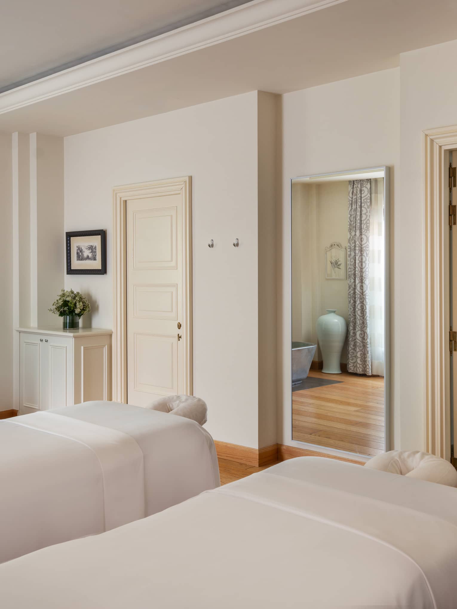 A light and spacious spa treatment room with two treatment tables side by side