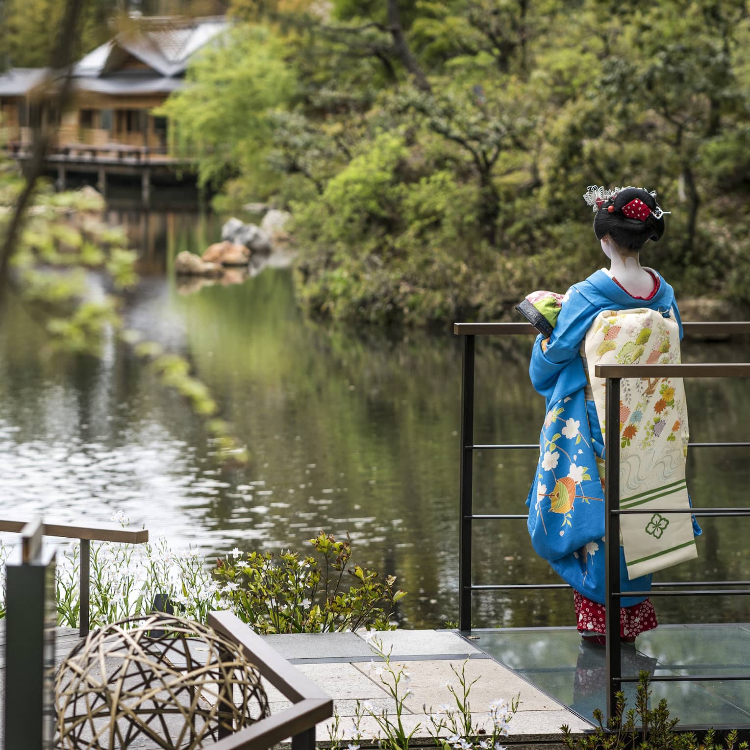 A woman in blue kimono gazing over the garden at Four Seasons Hotel Kyoto, a renowned luxury hotel in Kyoto.