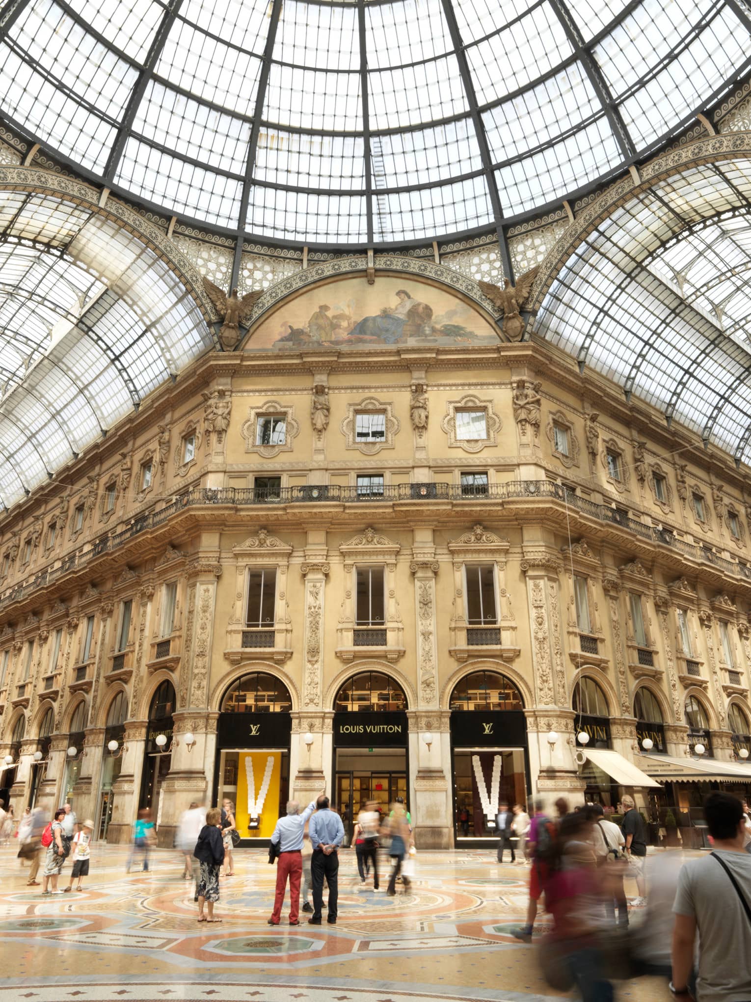 Shoppers gathered in historic Galleria Vittorio Emanuele building with soaring ceilings, shops