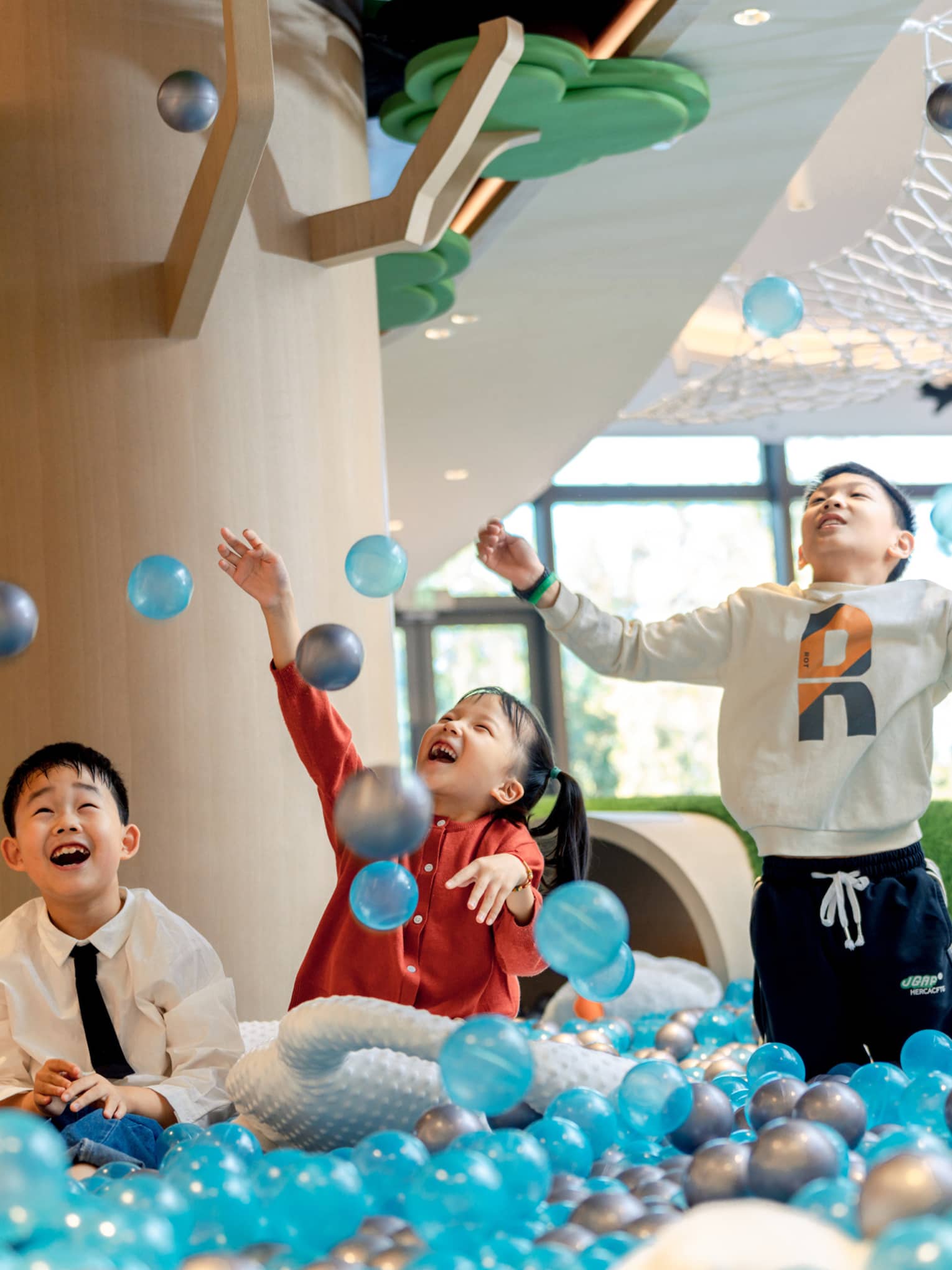 Three kids play in ball pit
