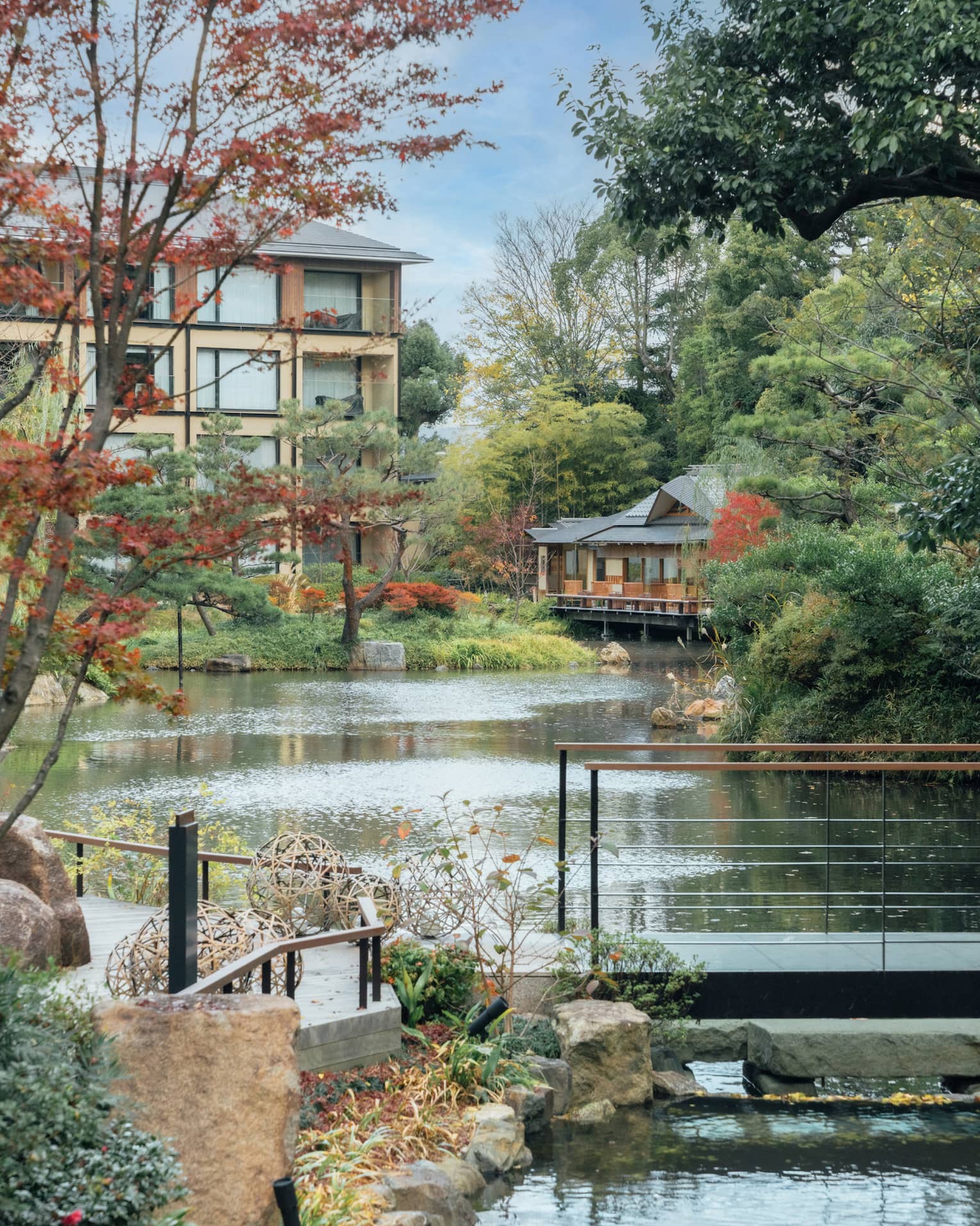 A pond surrounded by trees and crossed by a foot bridge