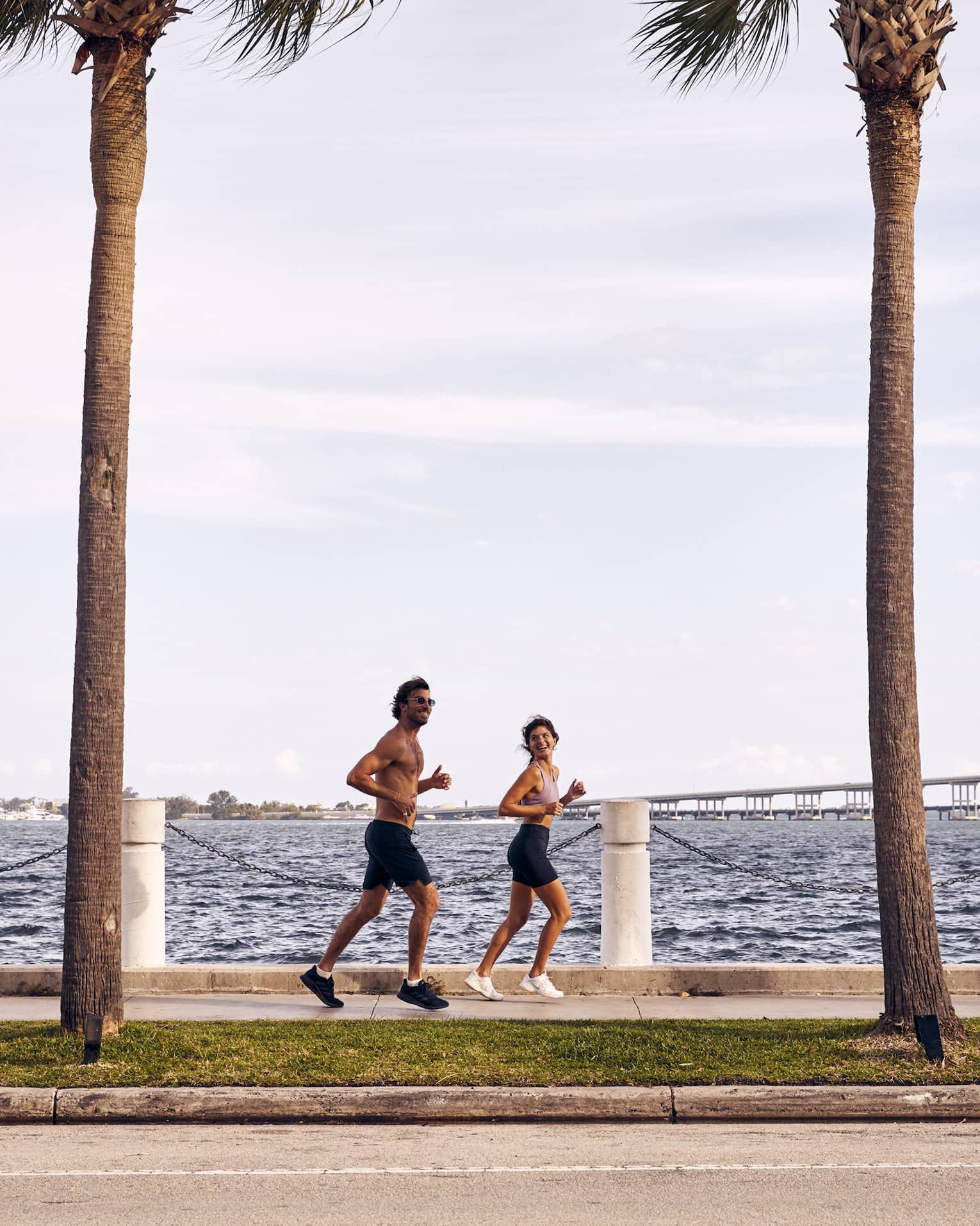 Man and woman running on sidewalk next to water