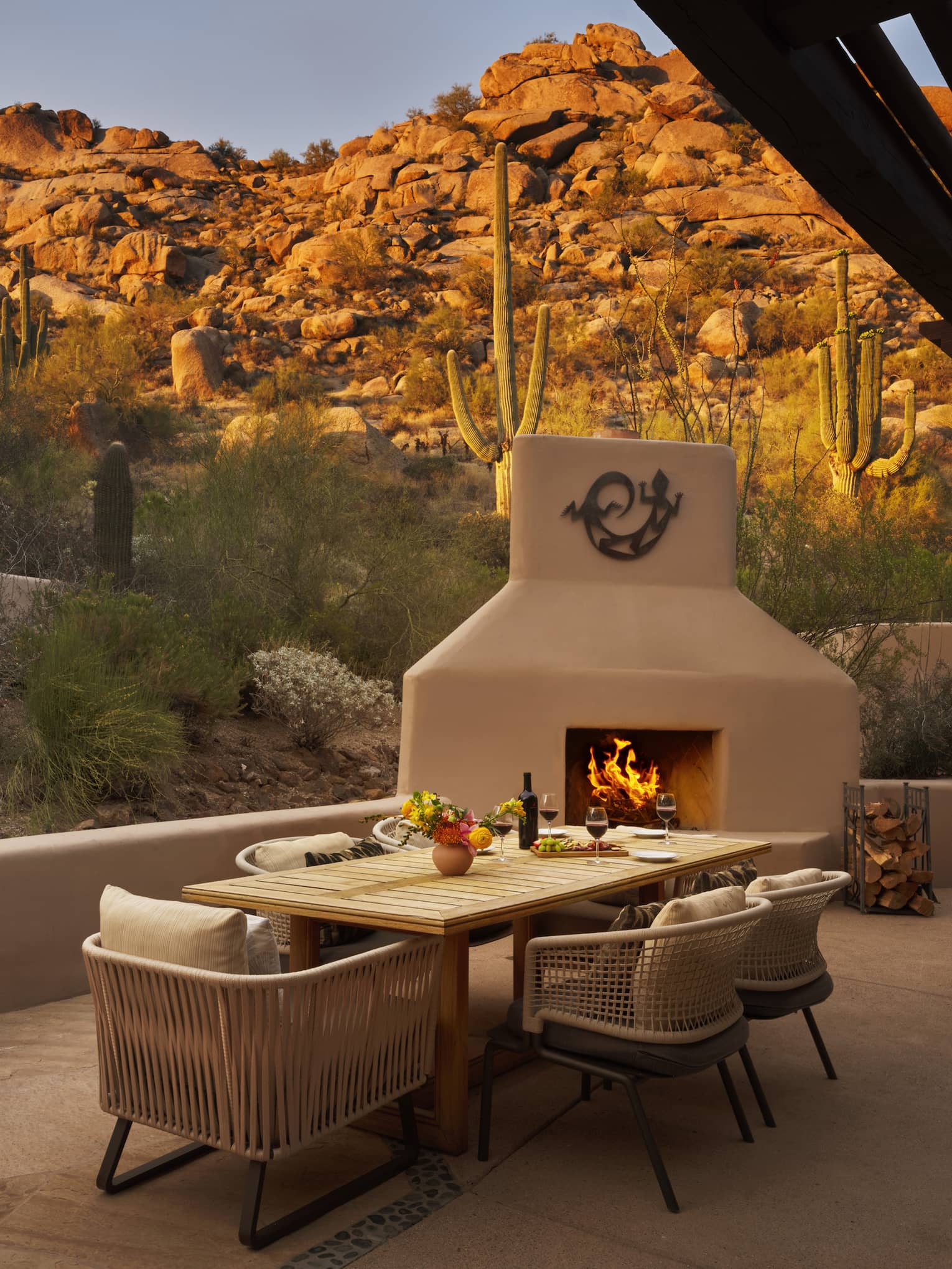 Private terrace of a resort suite, featuring a contemporary dining table, outdoor fireplace and views of the desert and rocky mountain