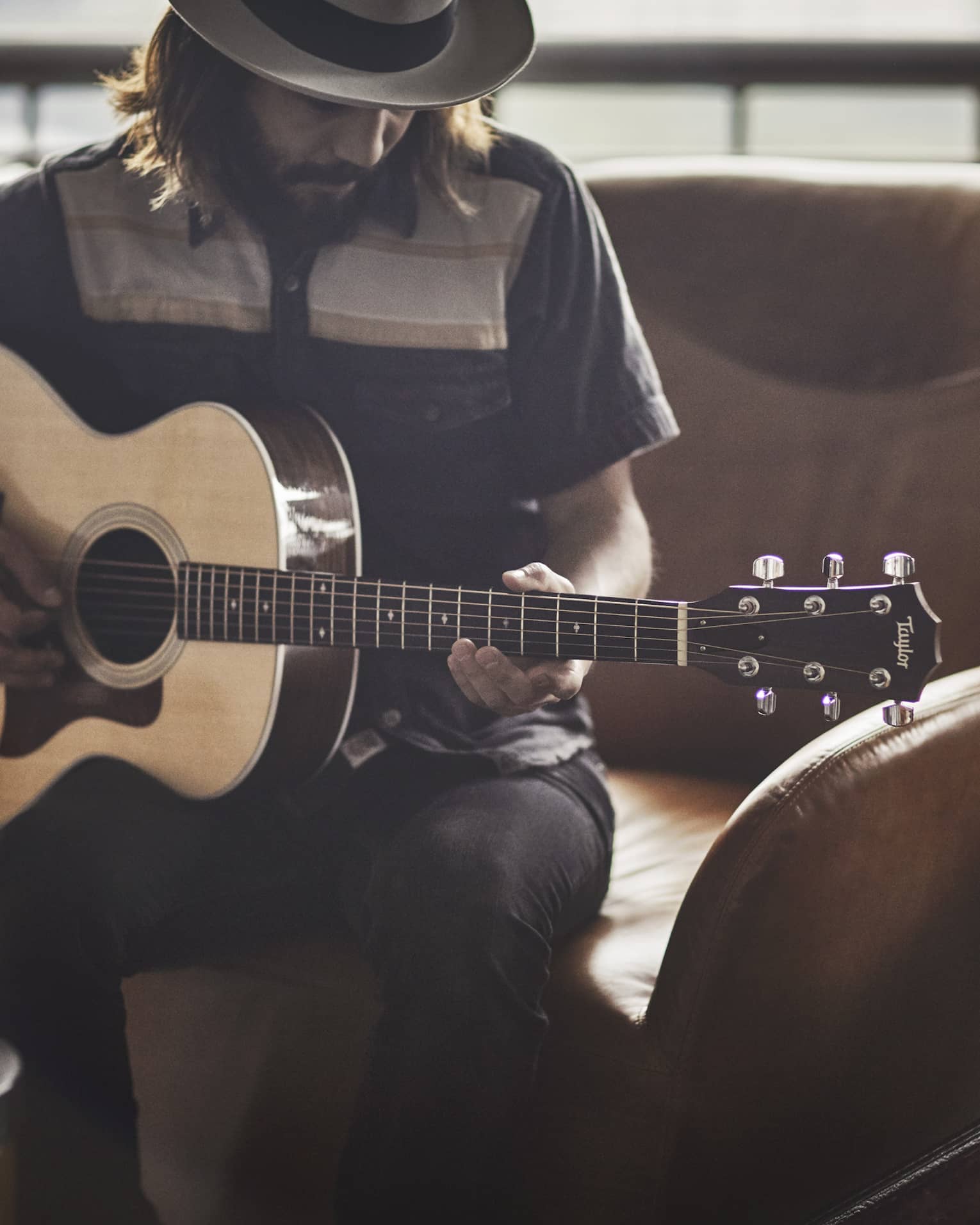 Guitar Concierge plays Taylor acoustic guitar on modern armchair