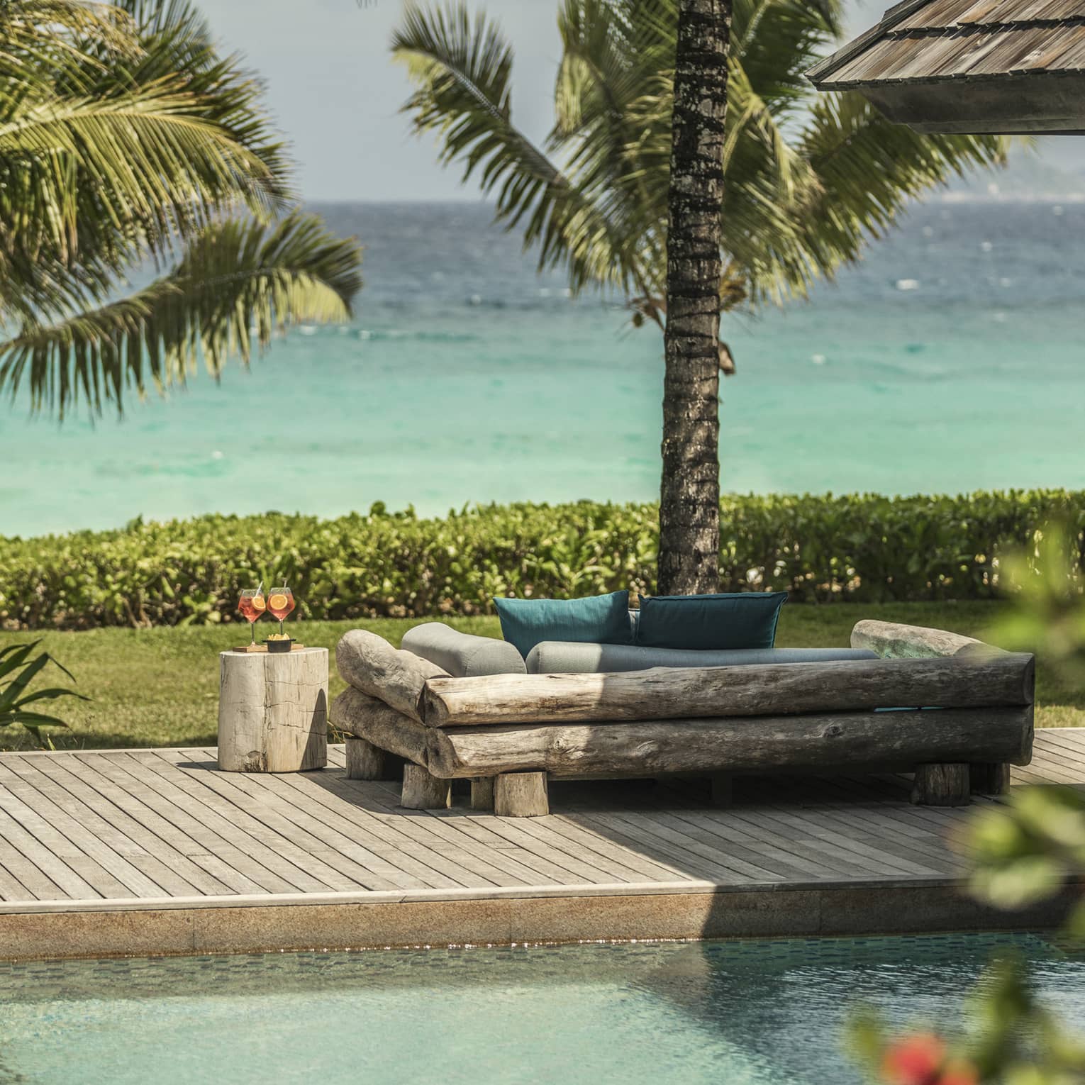 Kannel Bar swimming pool, wood deck, log loveseat looking out at palm trees, ocean