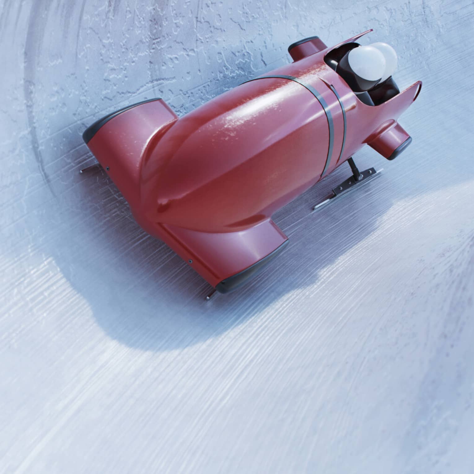 Front view of a bobsleigh zipping around a corner on a concave icy track, the helmets of two riders visible from the cockpit.