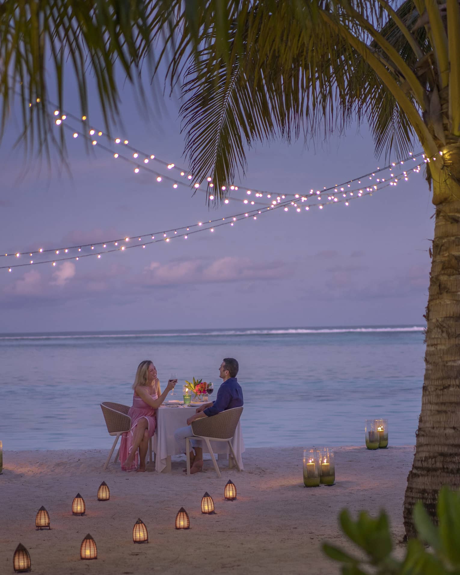 Man and woman dine at table for two alone on decorated beach