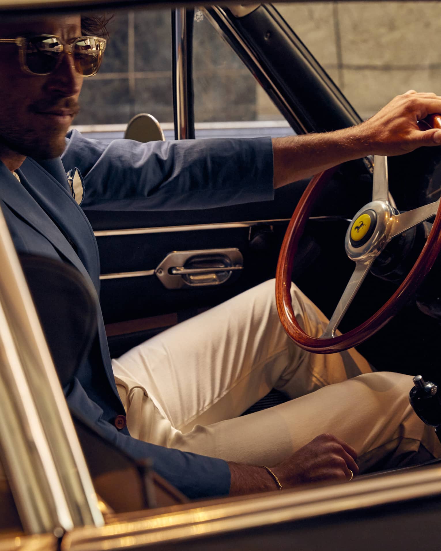 A man sitting in an older car with a suit on.