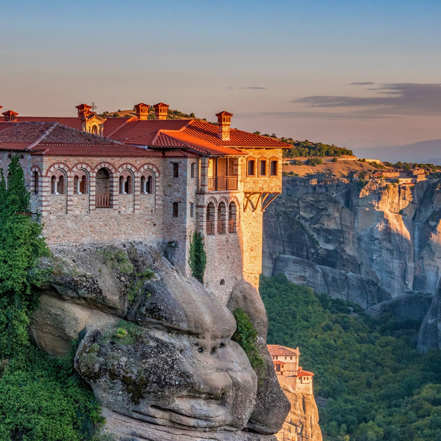 Ancient monastery on top of rock formation at sunset