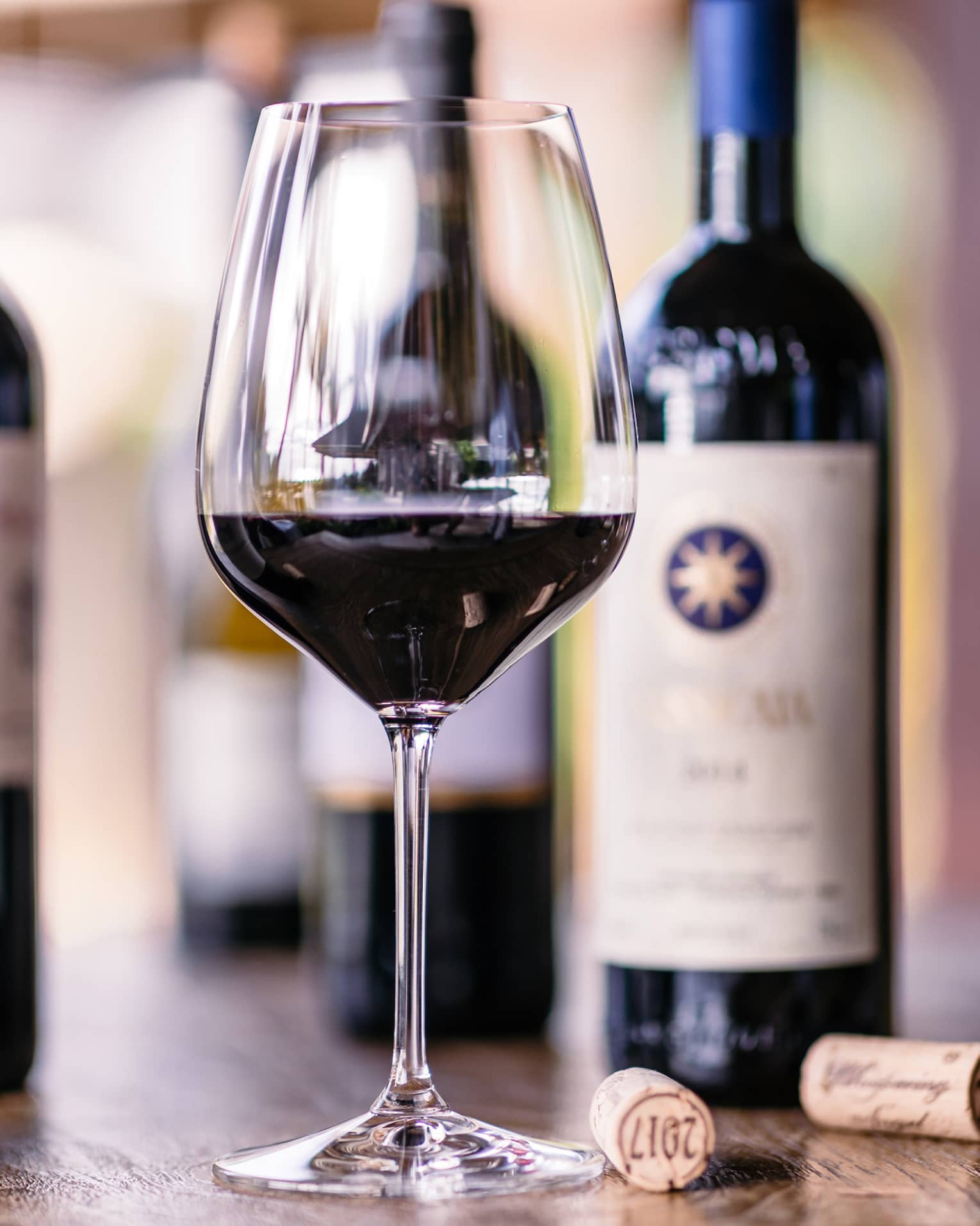Closeup of glass of red wine, bottles beside it