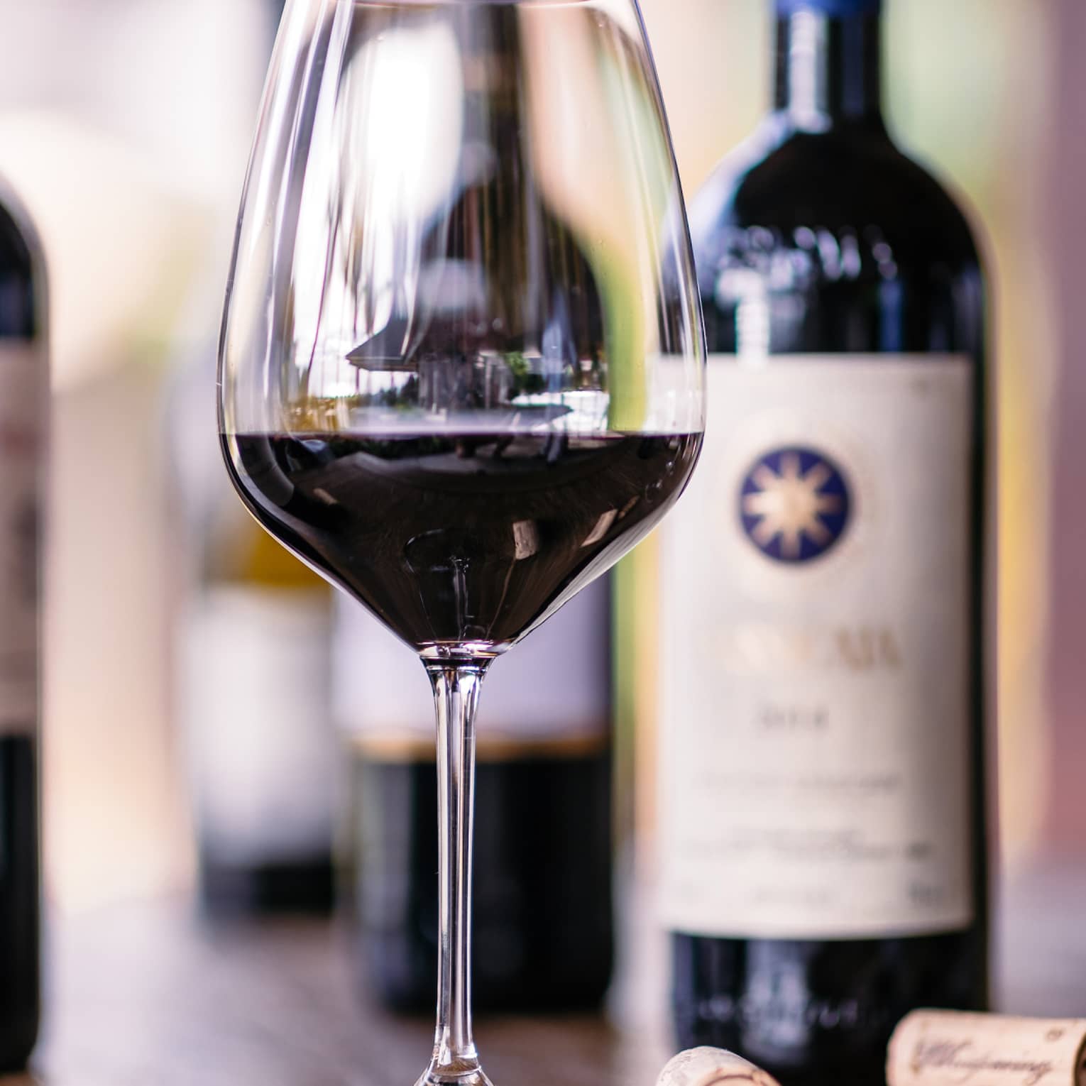 Closeup of glass of red wine, bottles beside it