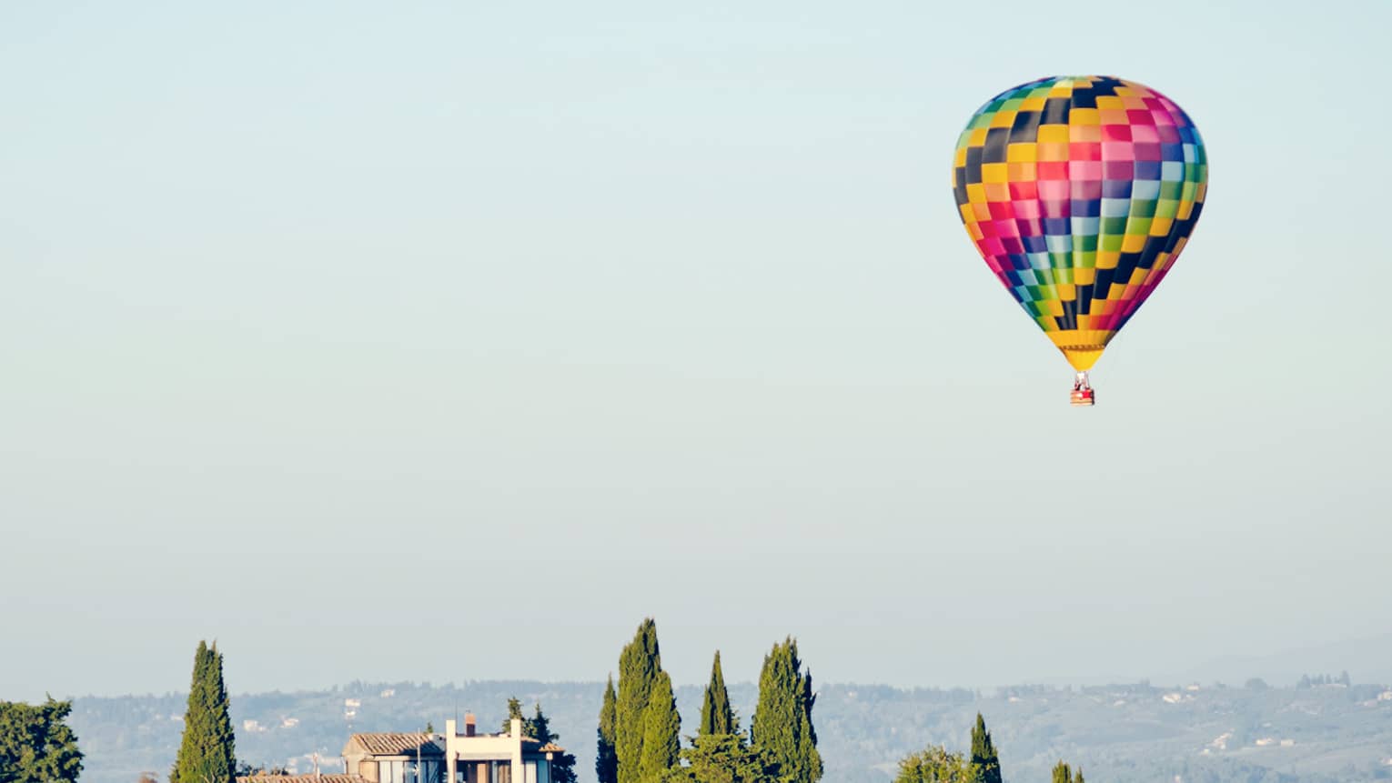 A colorful hot air balloon hovering over a vineyard in Florence