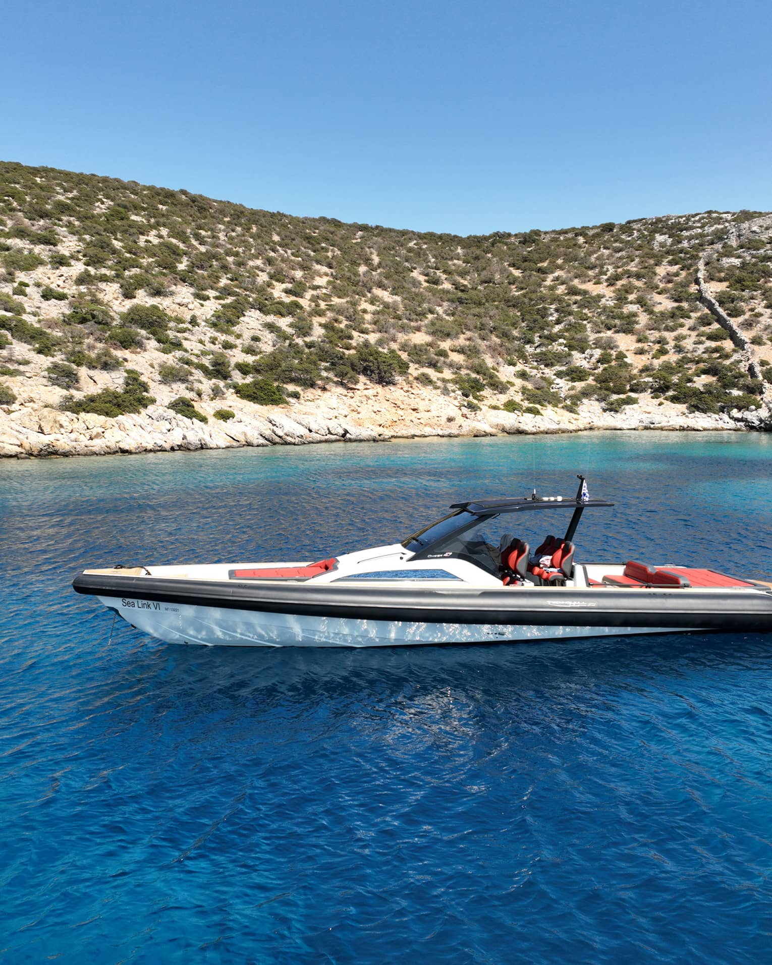 People swim behind a luxury boat in the blue waters close to the coast.
