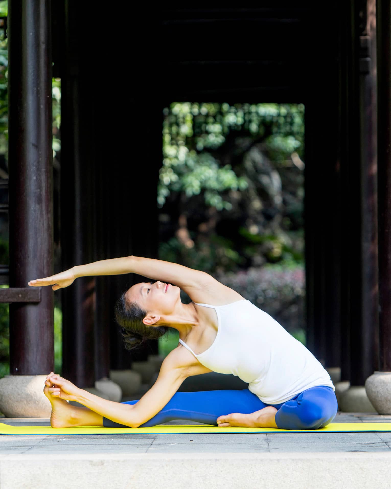 Woman wearing exercise clothes stretches legs, arms on yoga mat
