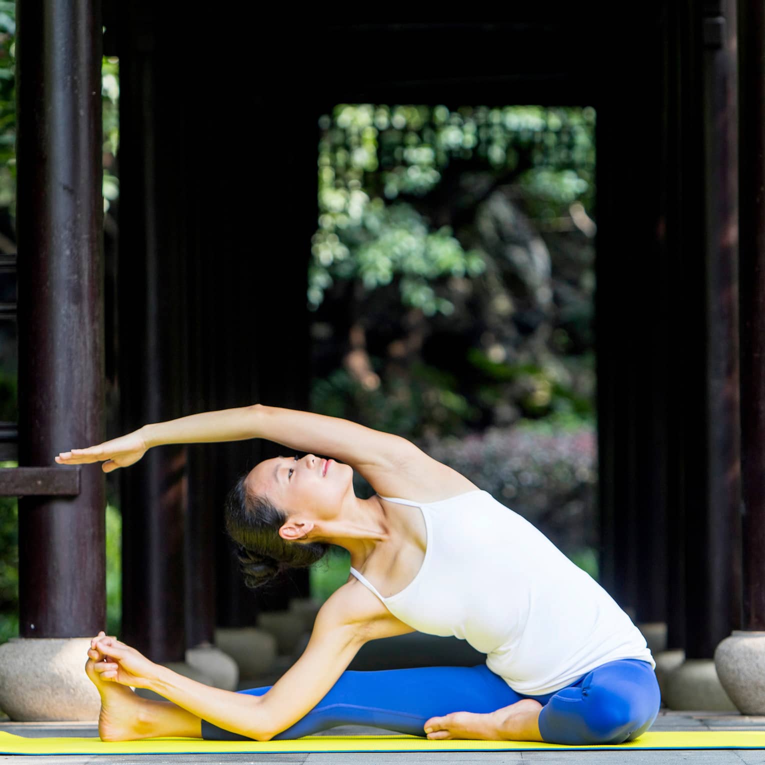 Woman wearing exercise clothes stretches legs, arms on yoga mat