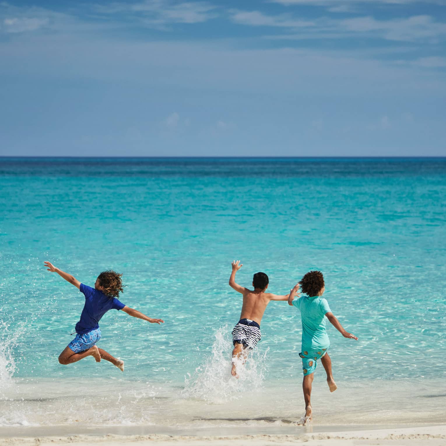 Children running into water from a beach.