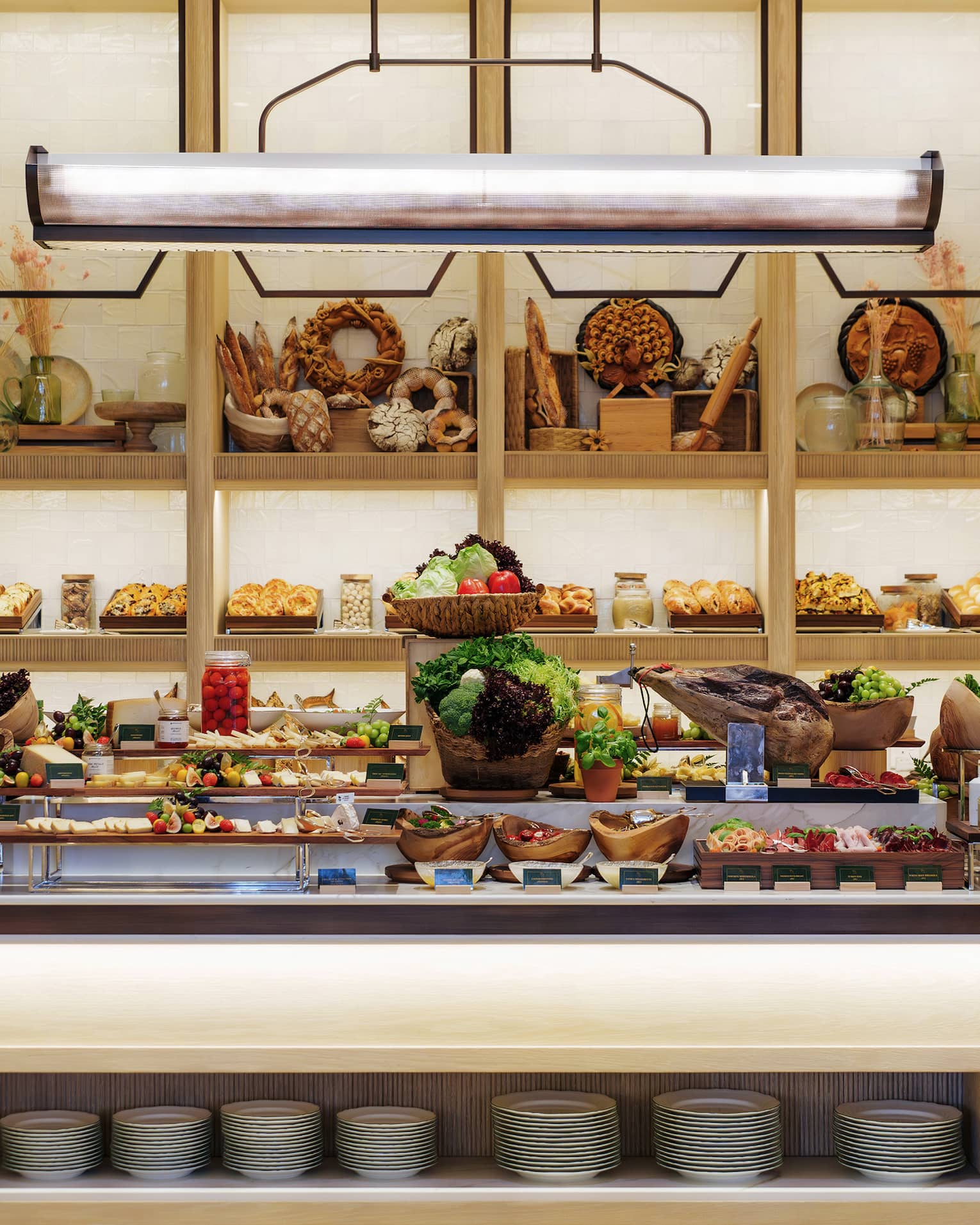 Breakfast buffet display on a large centre island with shelves of break and baked goods in the background