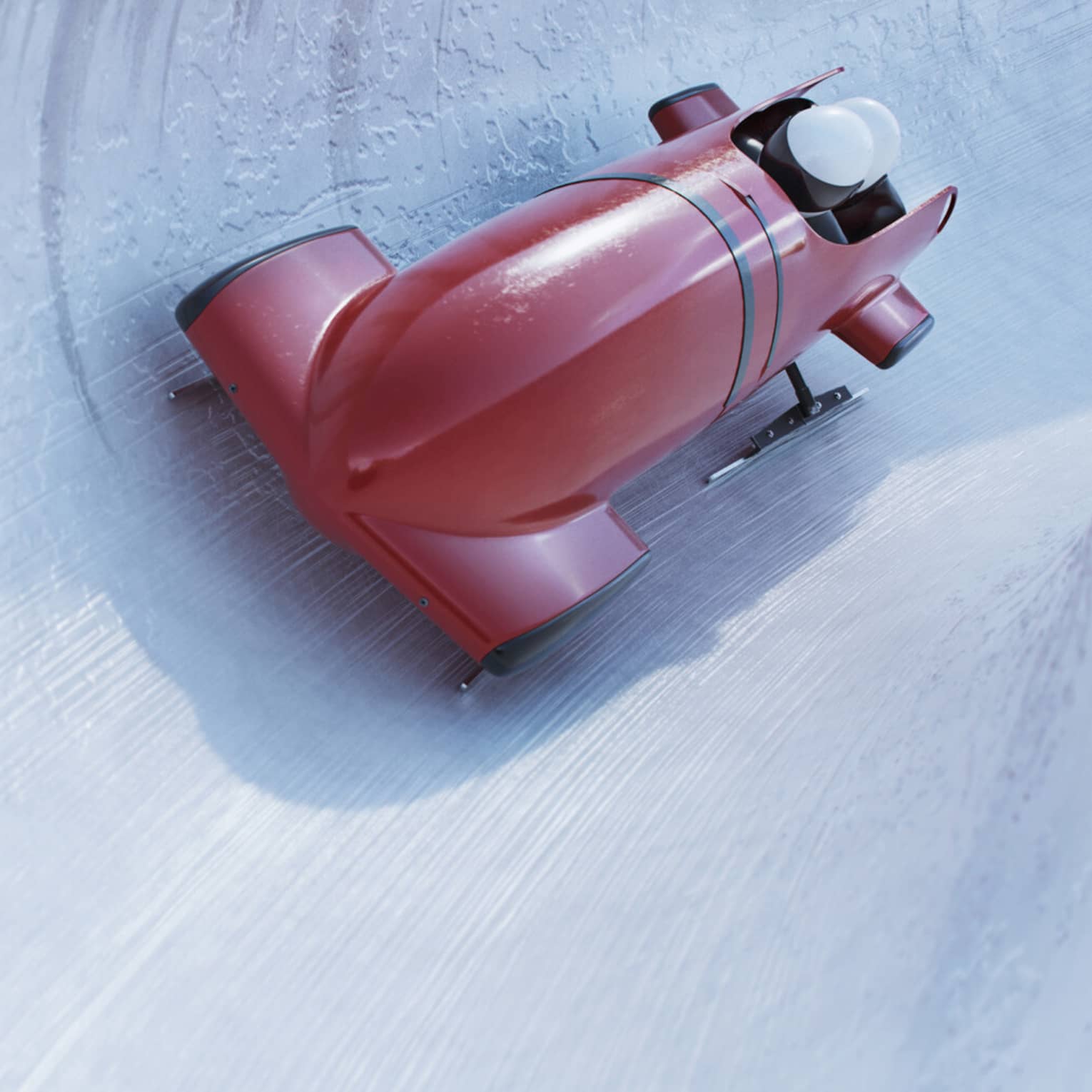 Front view of a bobsleigh zipping around a corner on a concave icy track, the helmets of two riders visible from the cockpit.